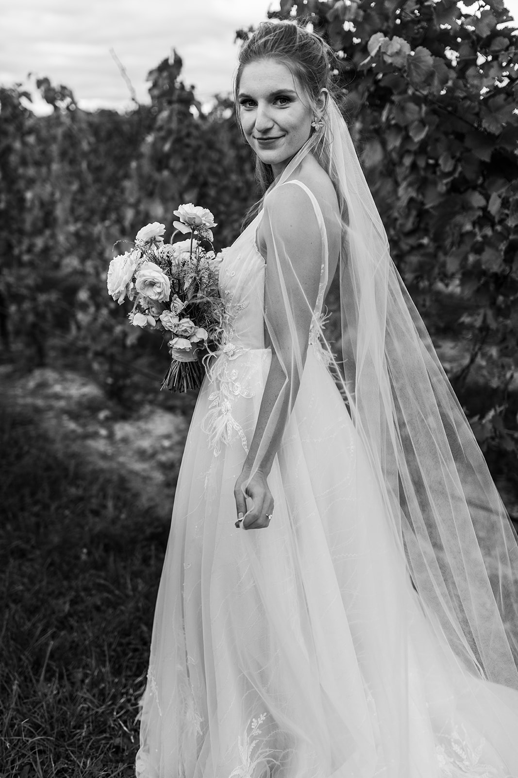 Bride wedding photos in vineyard with flower bouquet and long veil