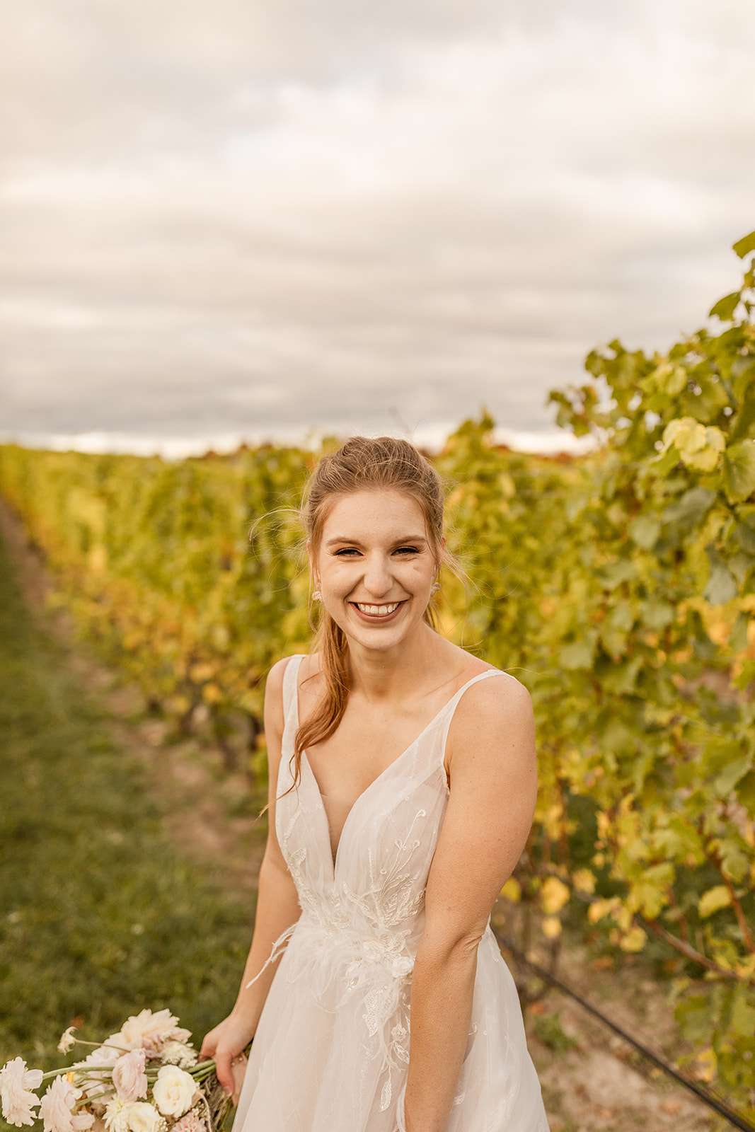Bride laughing in vineyard with floral bouquet in Michigan
