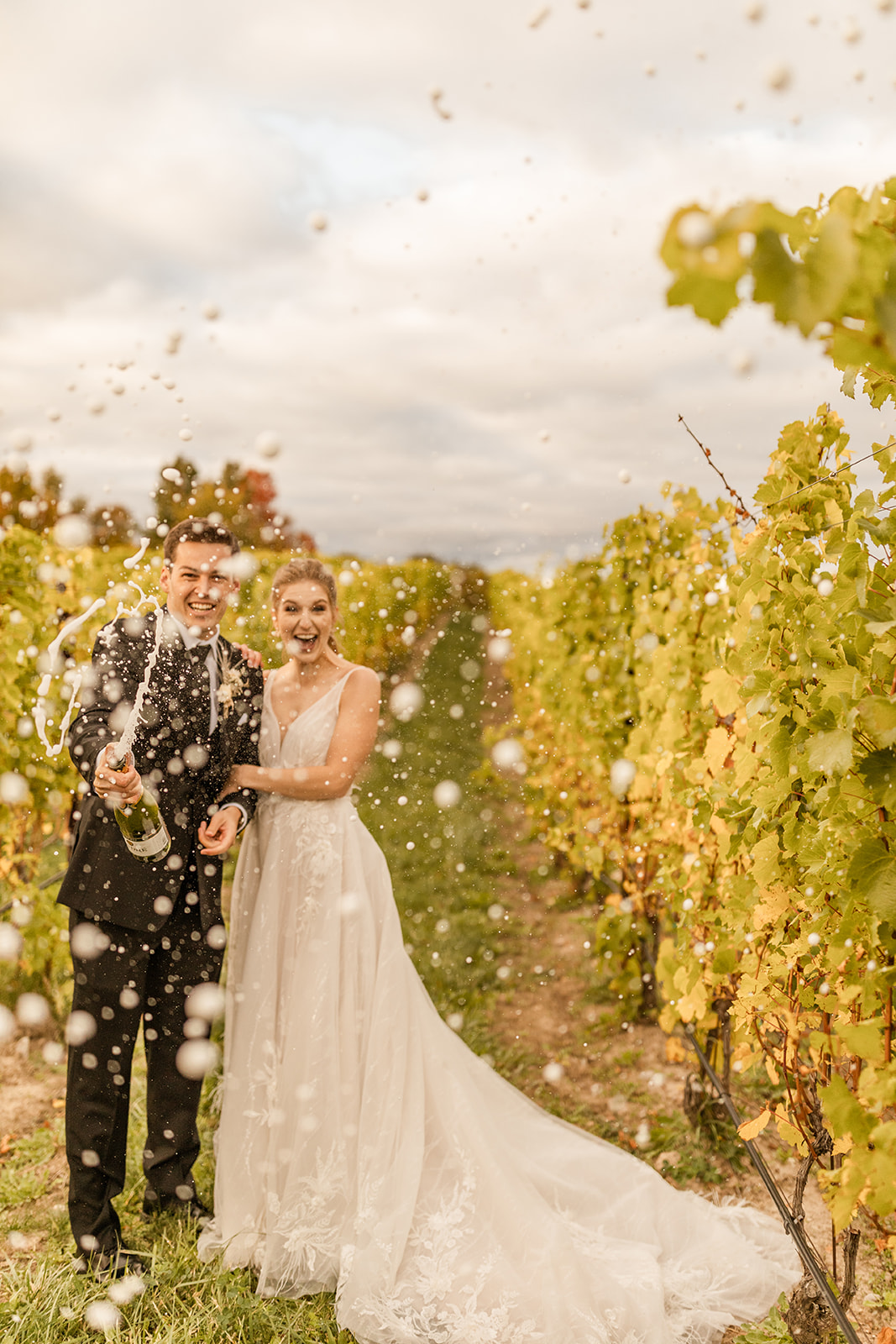 Bride and groom popping champagne in vineyard for Northern Michigan elopement