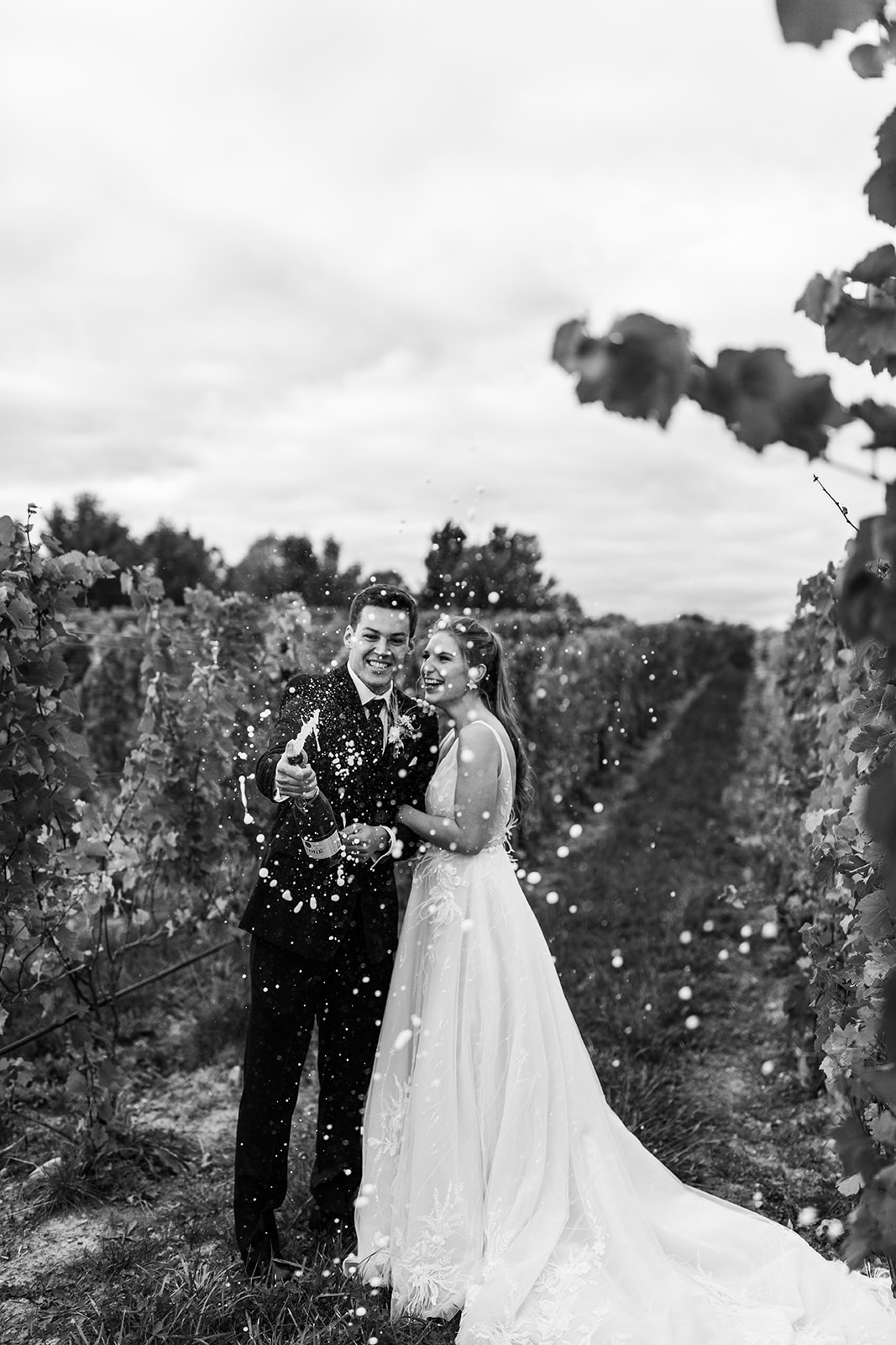 Bride and groom popping champagne at vineyard wedding in Michigan