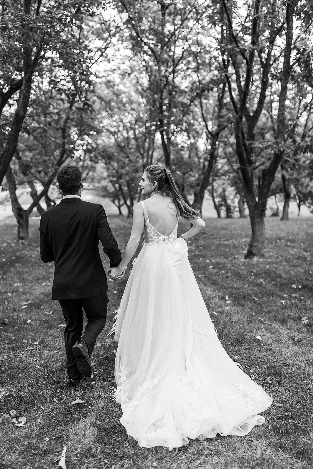 Bride and groom walking through wooded path
