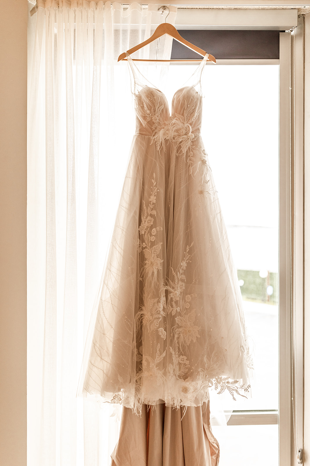 wedding dress hanging up in front of window