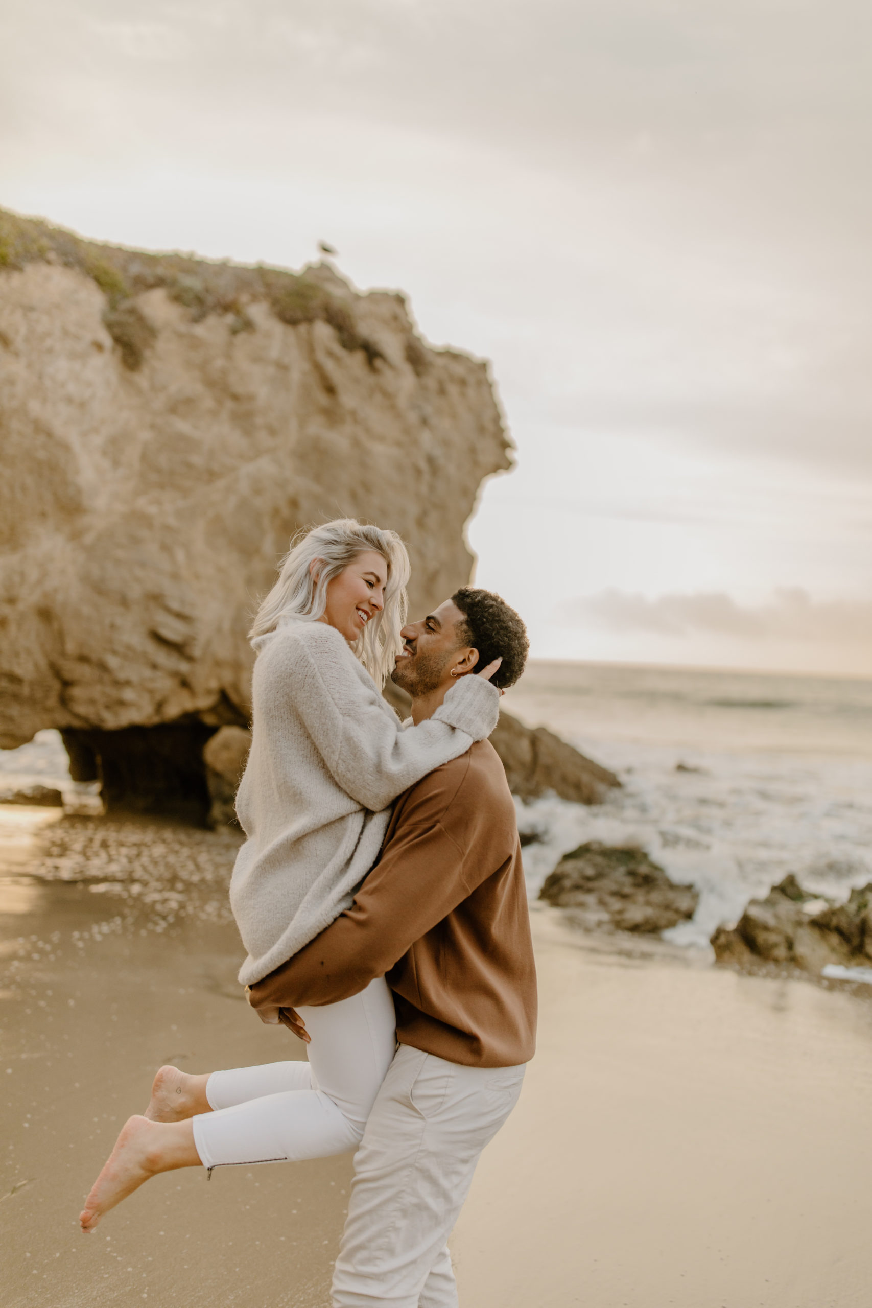 couple holding eachother at california beach engagement session