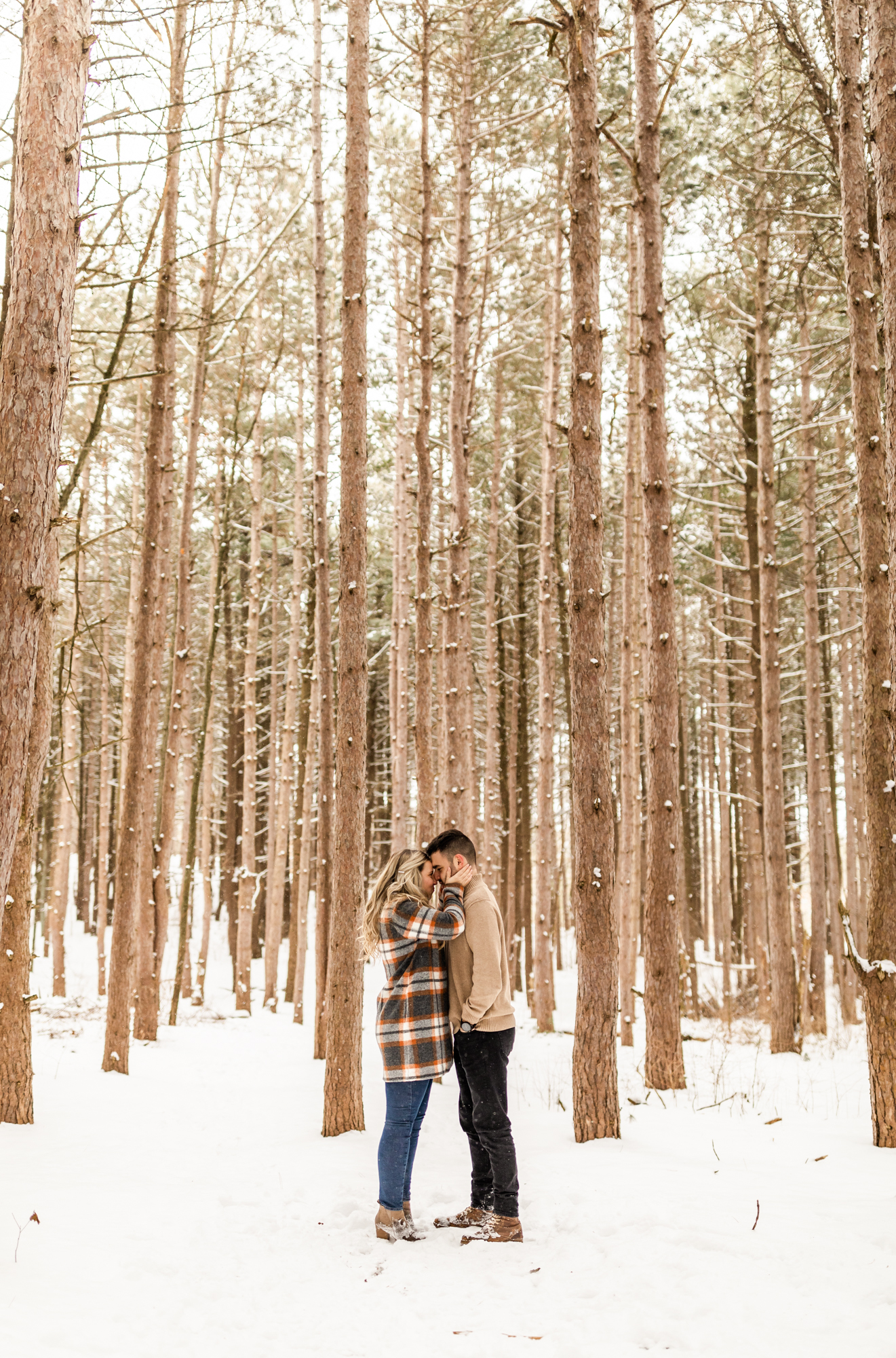 Couple standing together in snowy woods for engagement photo, outfit inspiration 