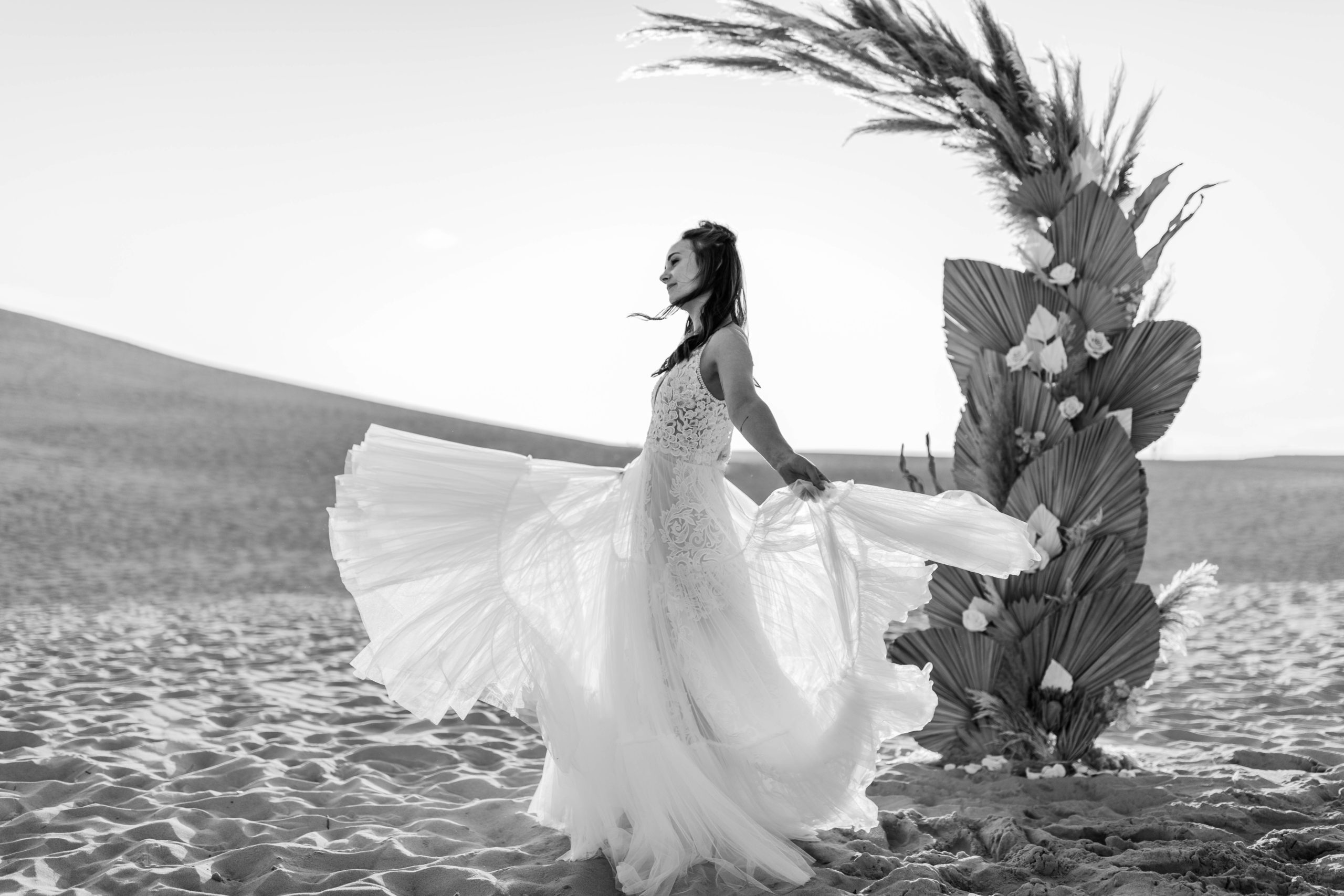 bride twirling in Sand Dune in front of Palms and Pampas Grass