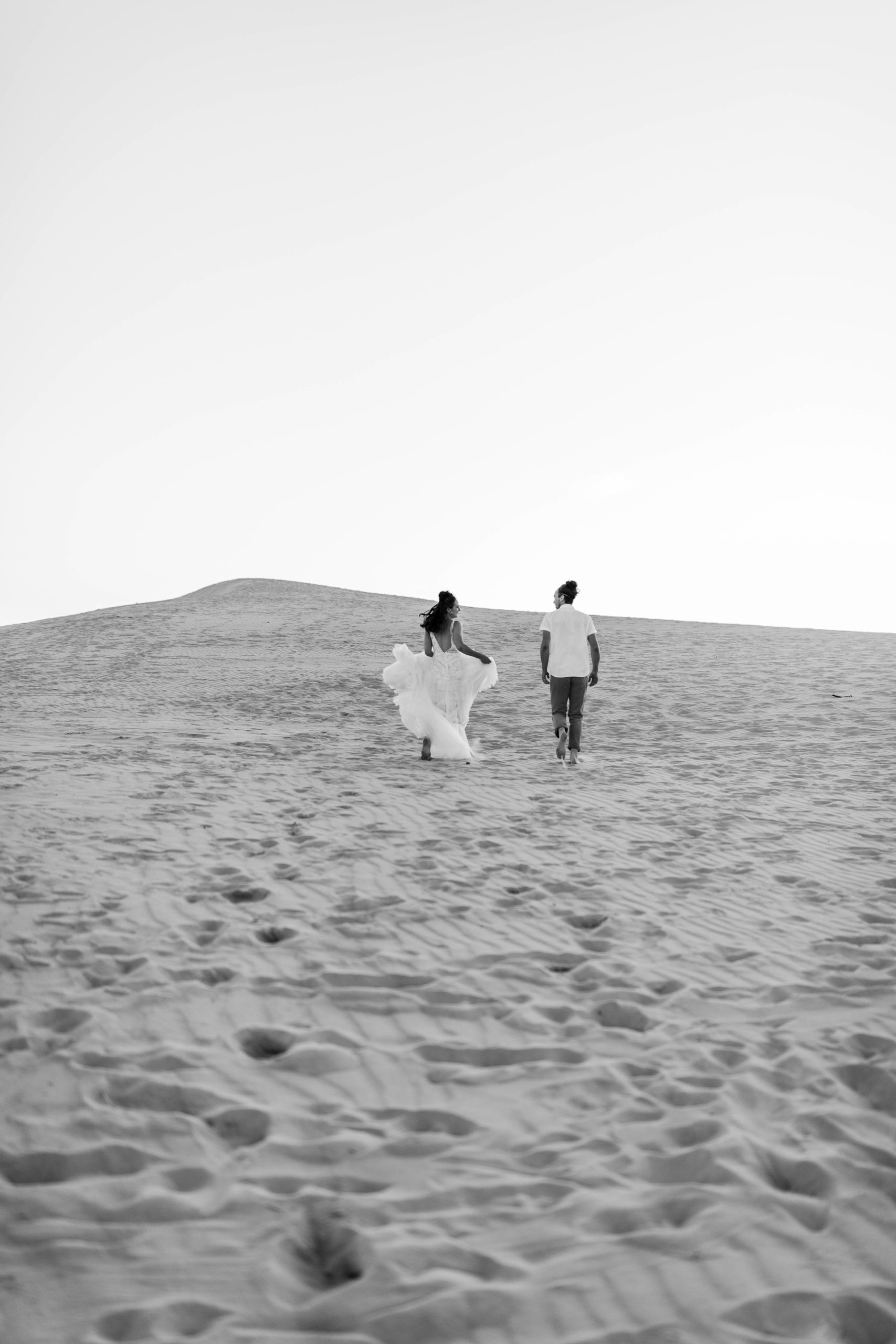 bride and groom running on sand dune in Michigan elopement