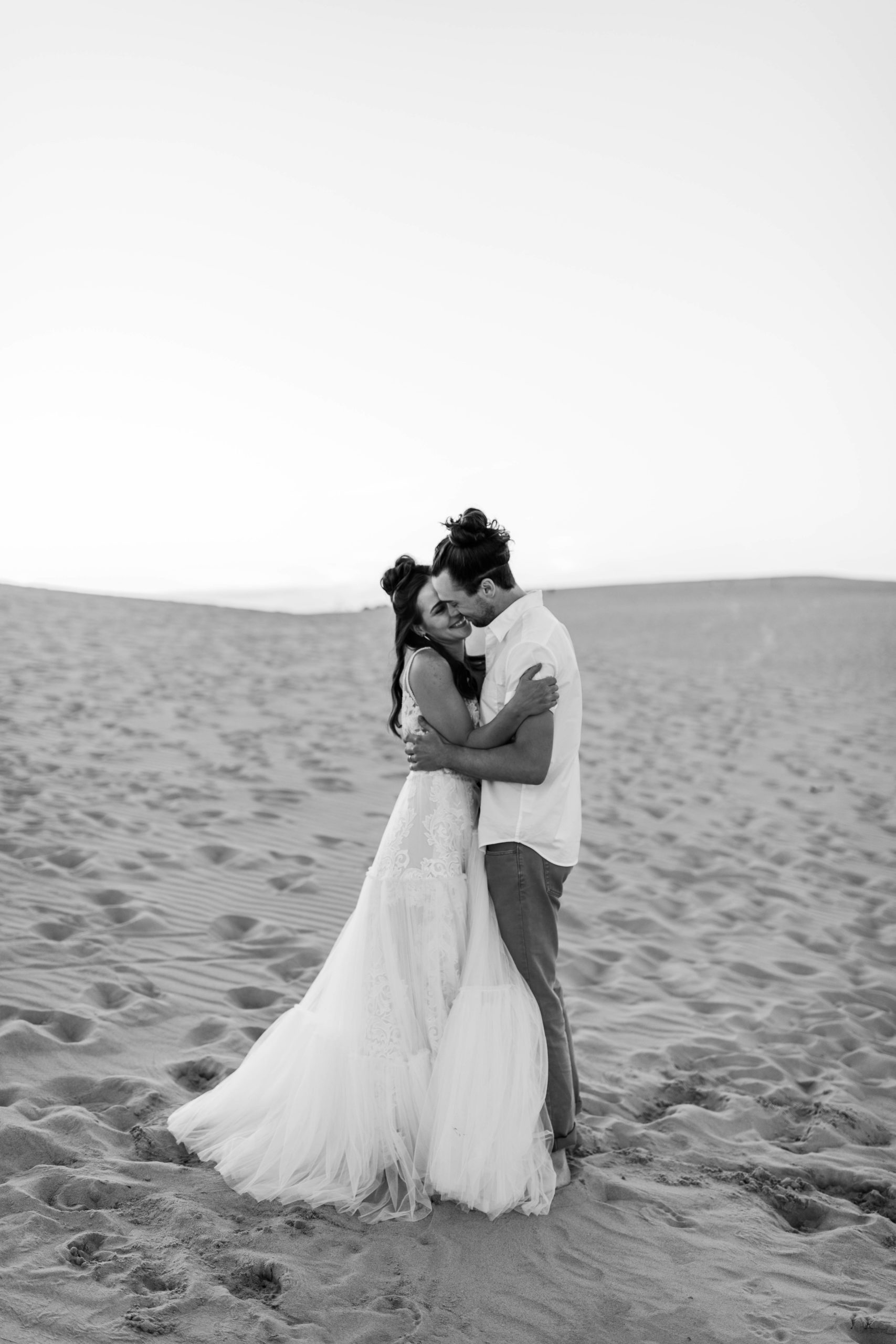 bride and groom hugging on sand dune in Michigan