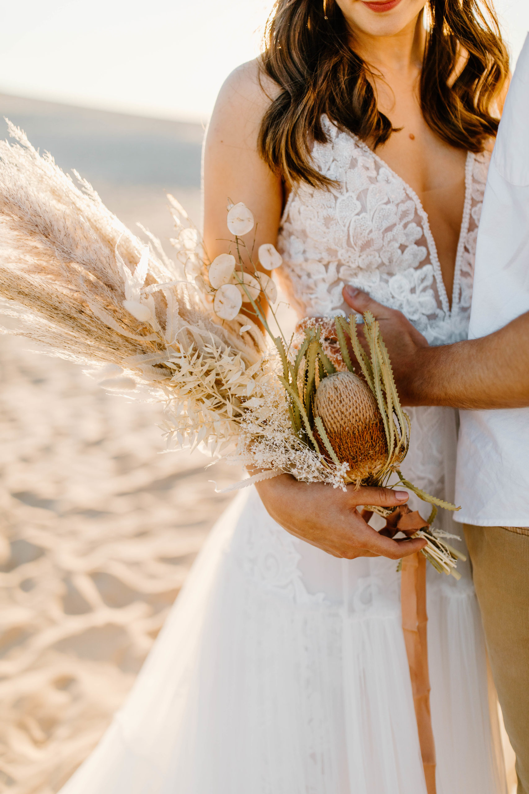 bride holding boho bouquet of dried flowers and pampas grass