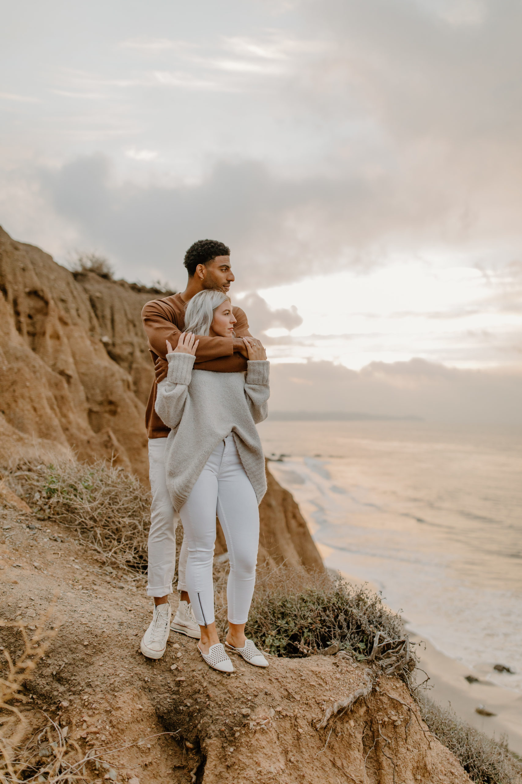 couple hugging on top of cliff overlooking ocean Malibu engagement photos California photographer