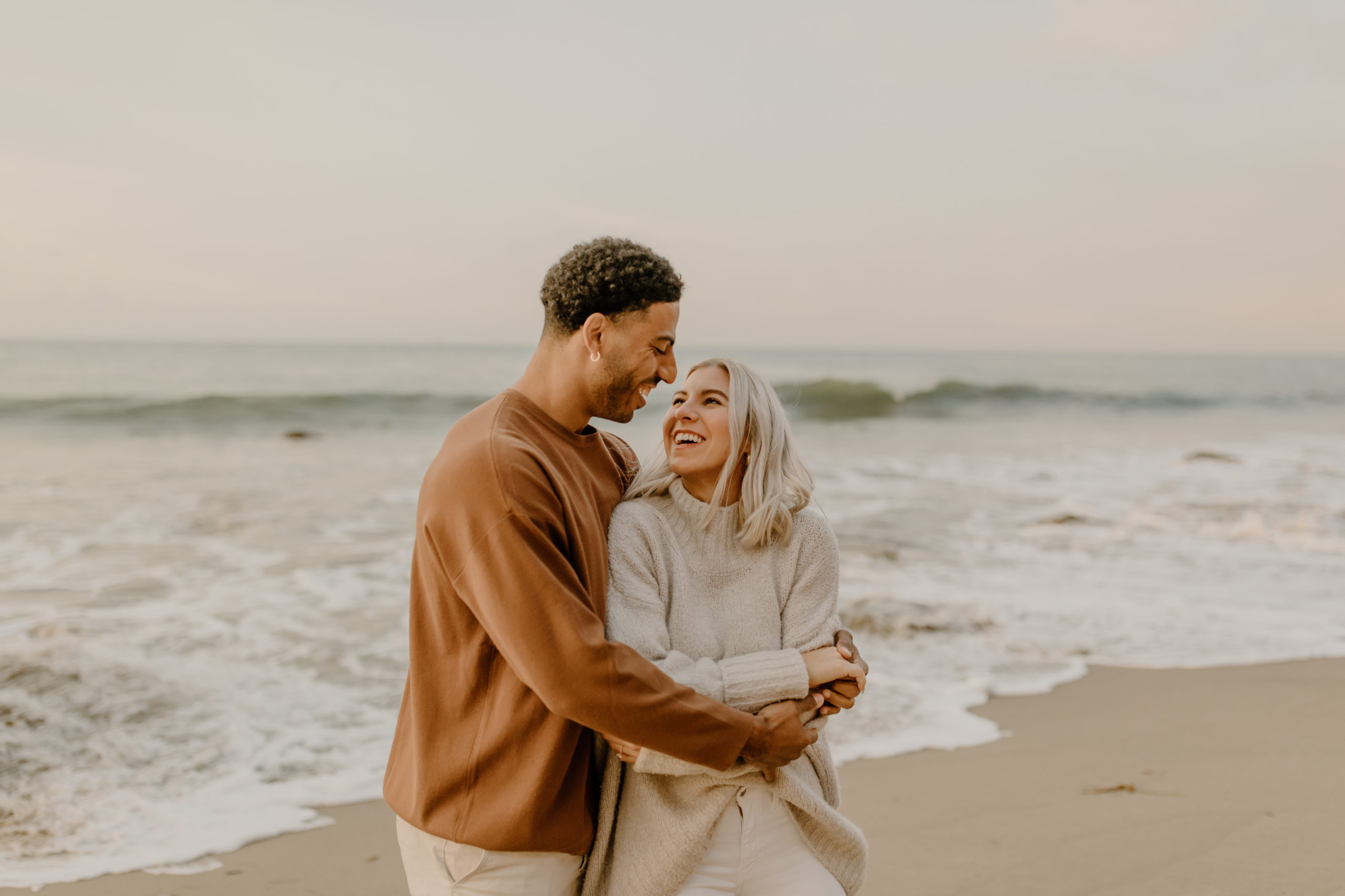 couple hugging on beach in California for sunrise engagement photo session