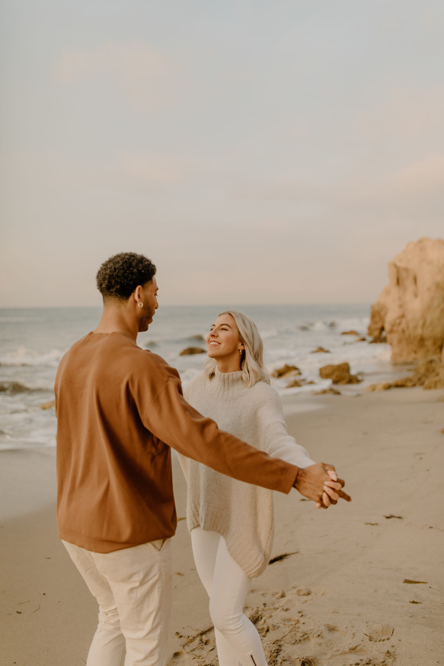 couple holding hands on beach in California engagement photoshoot