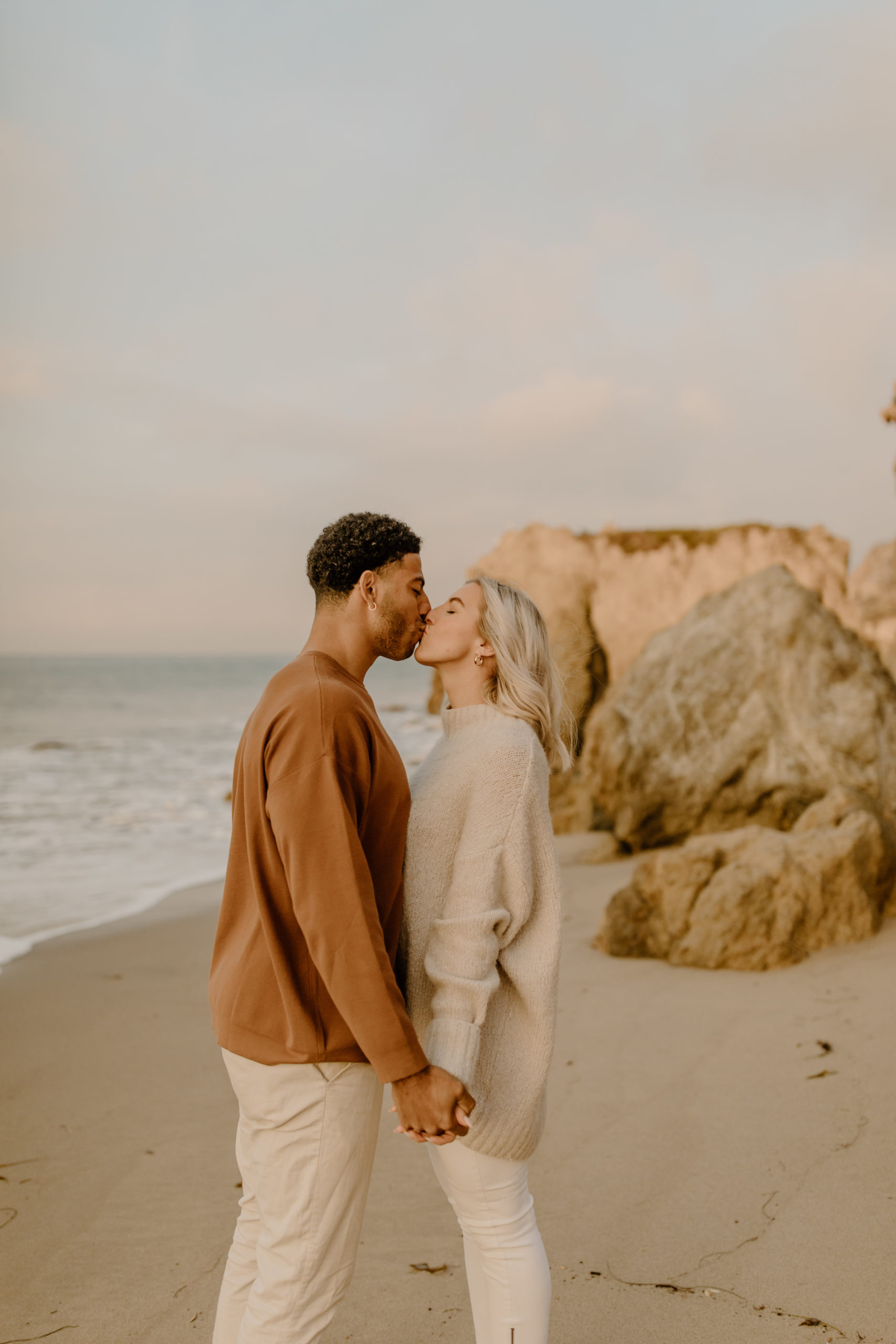 couple kissing on beach in California candid engagement photoshoot