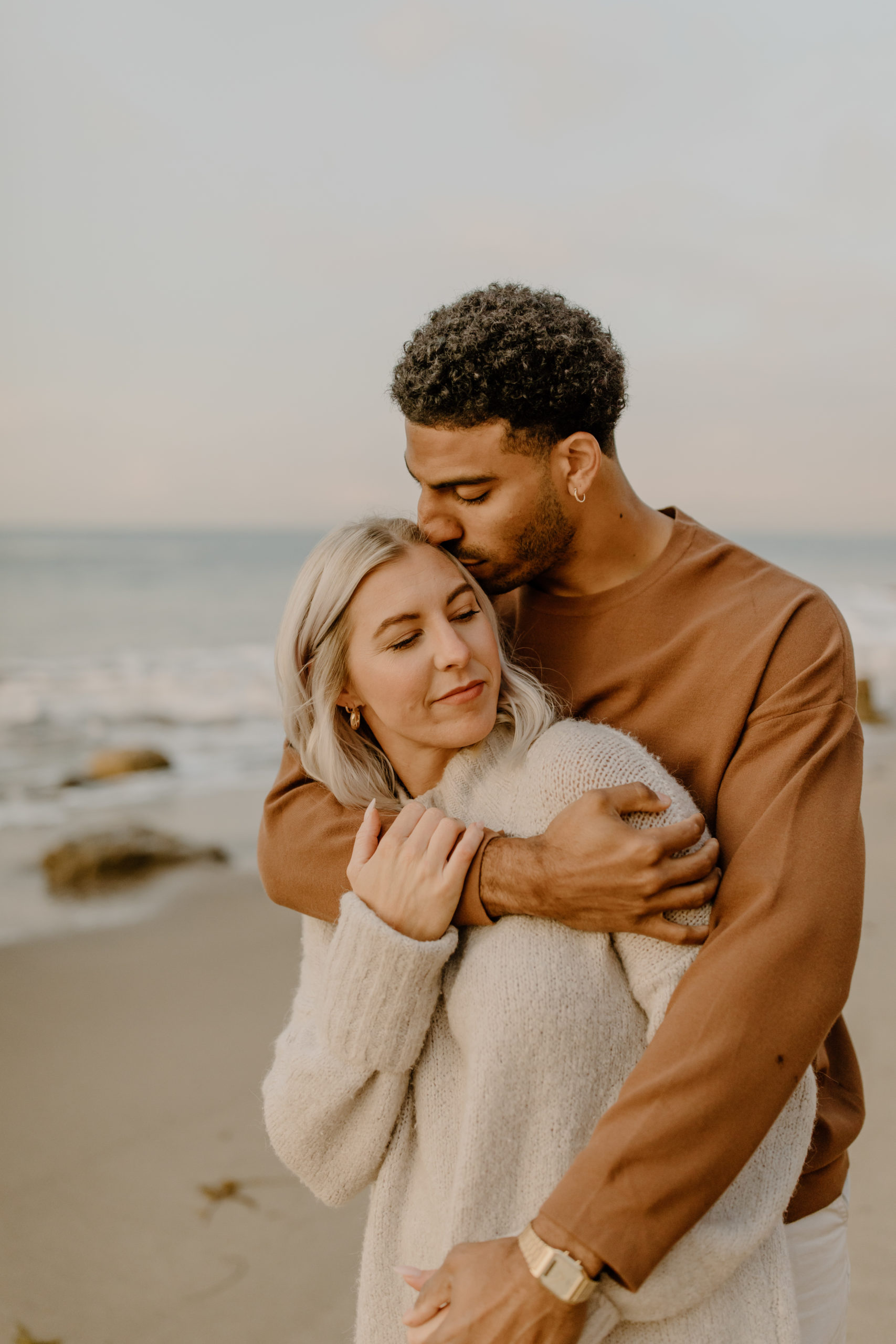 couple hugging on beach in California for engagement photoshoot