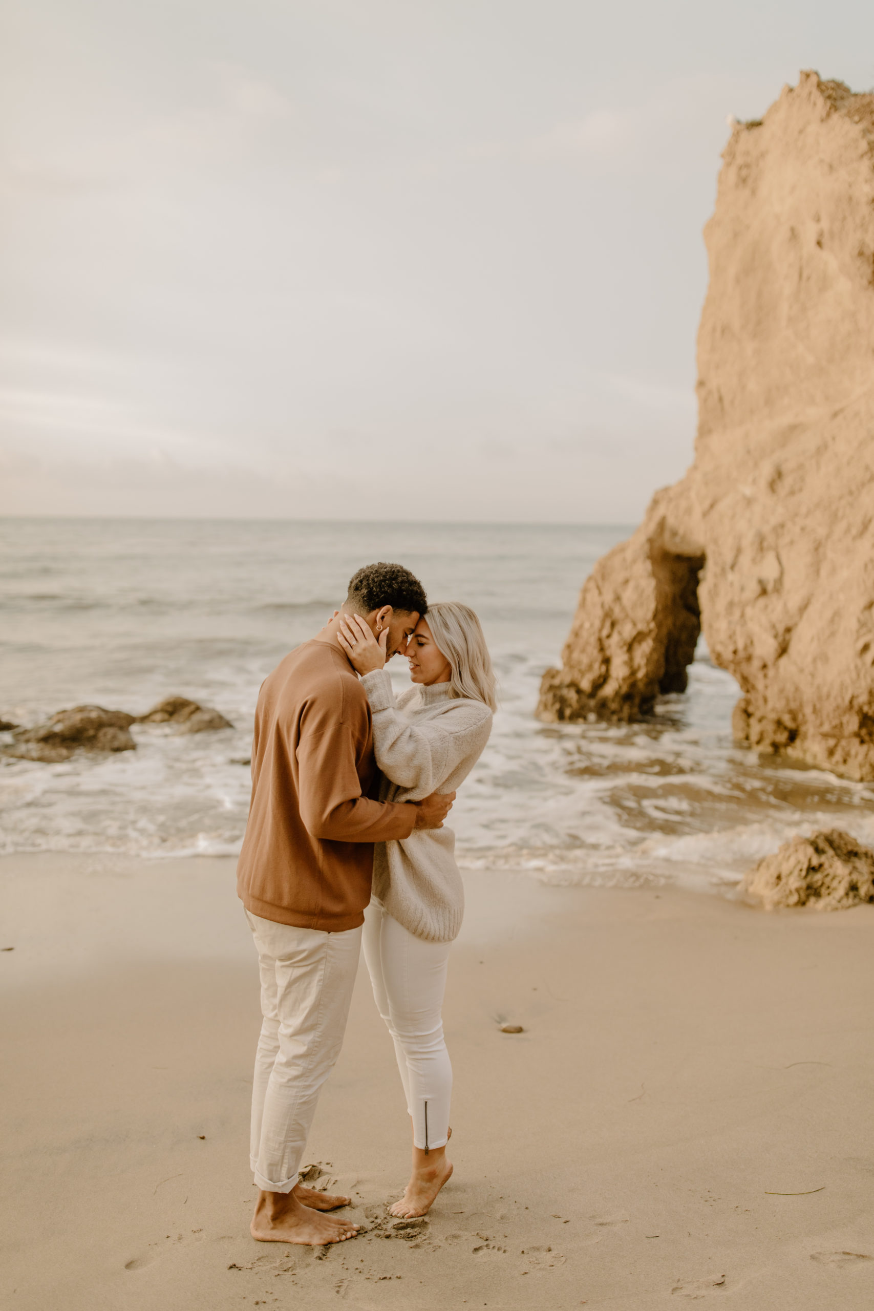 couple hugging on beach in California by the ocean