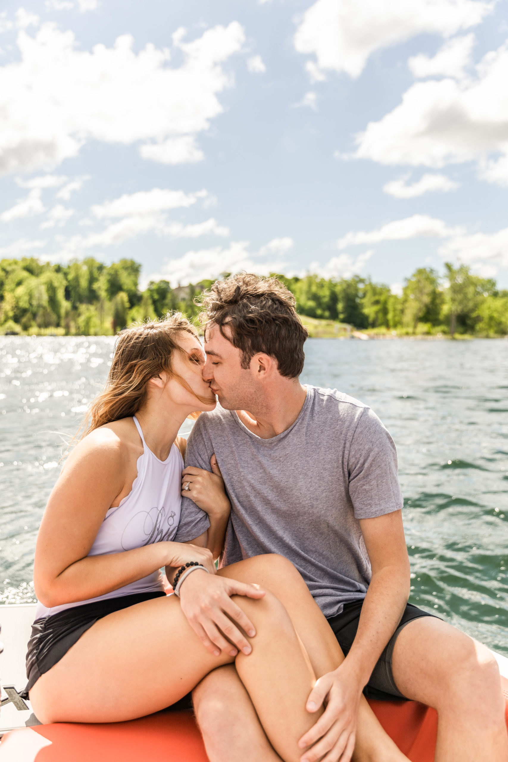 couple kissing on mastercraft boat in lake michigan surfign photoshoot