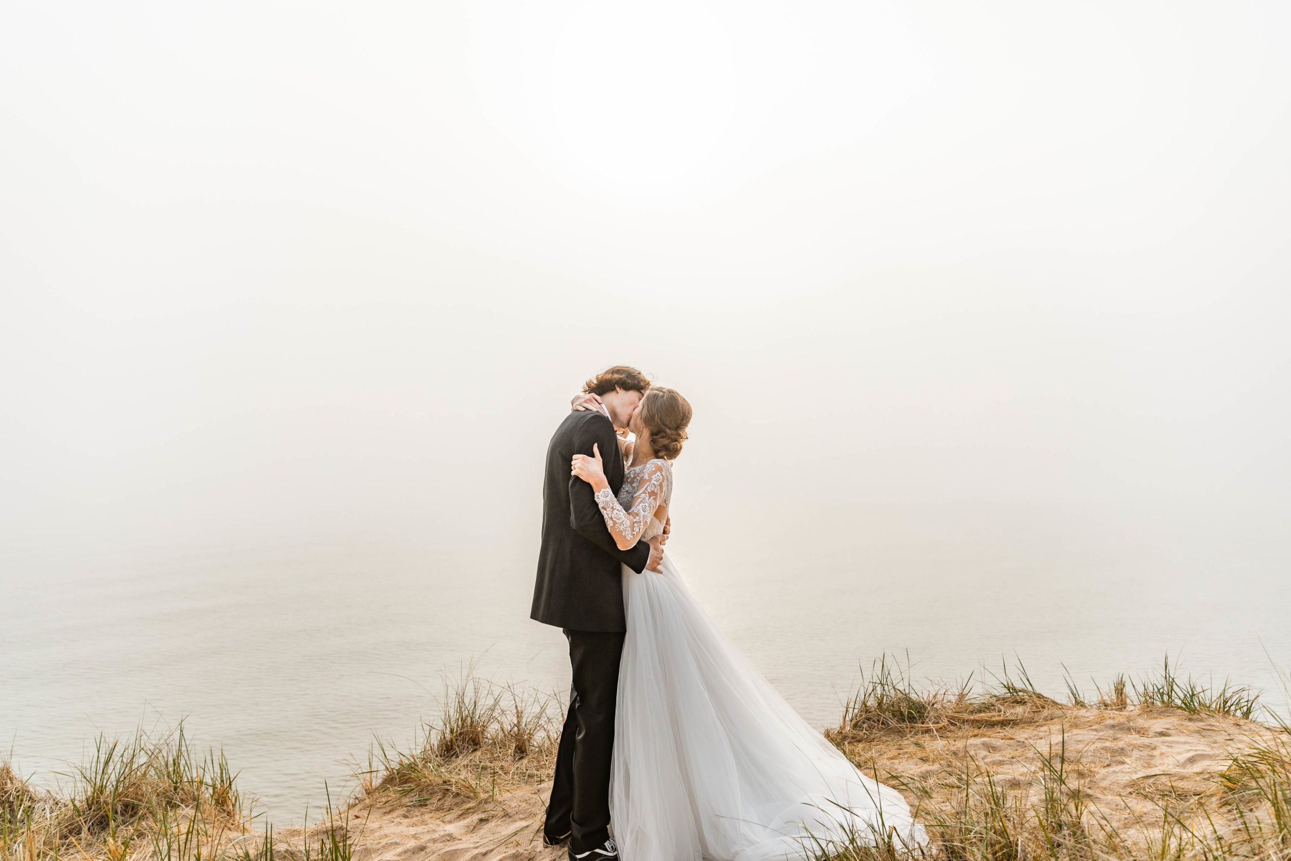 Bride and Groom kissing on dune overlooking Lake Michigan 