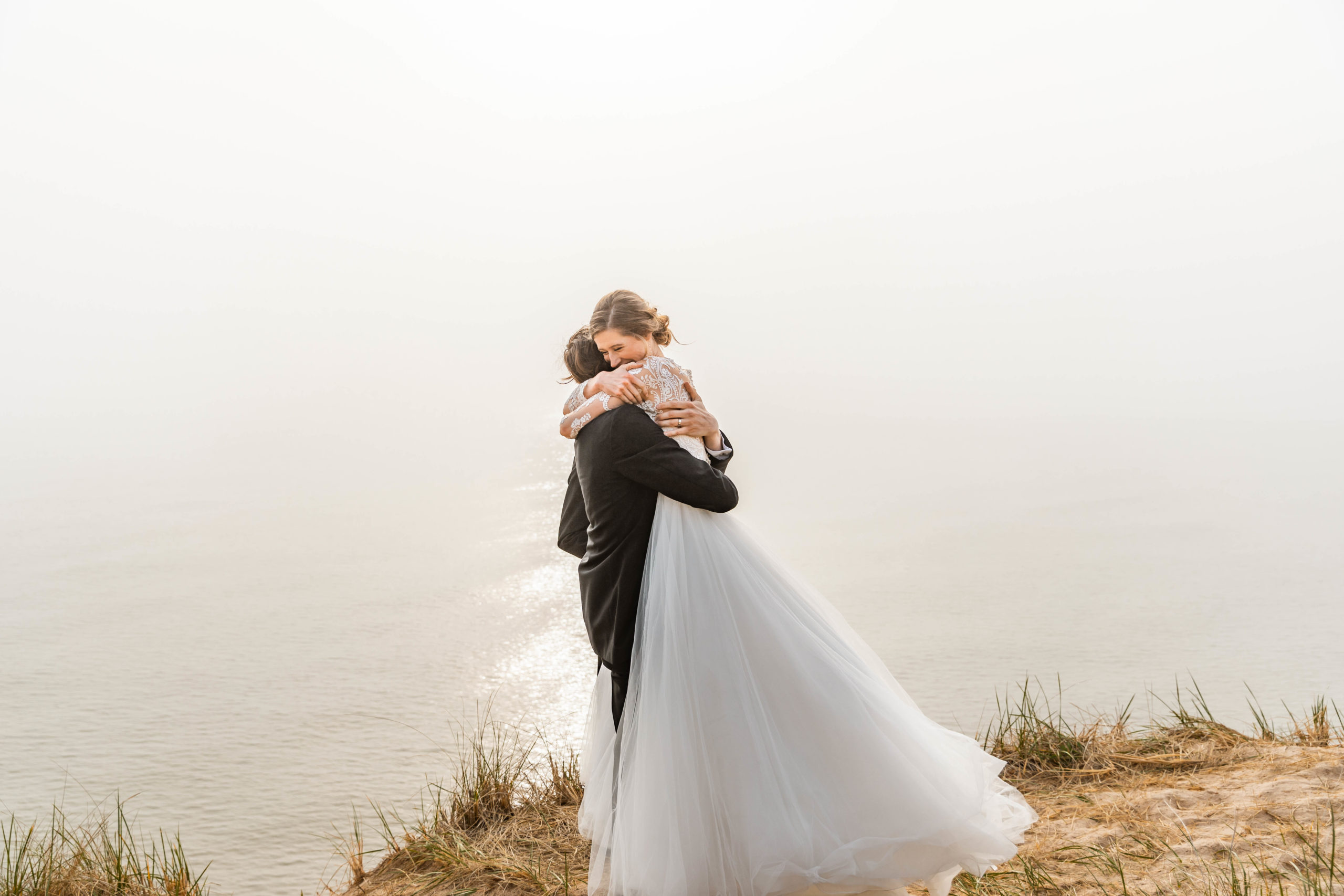 Bride and Groom hugging on sand dune elopement in wedding dress by Lake Michigan beach