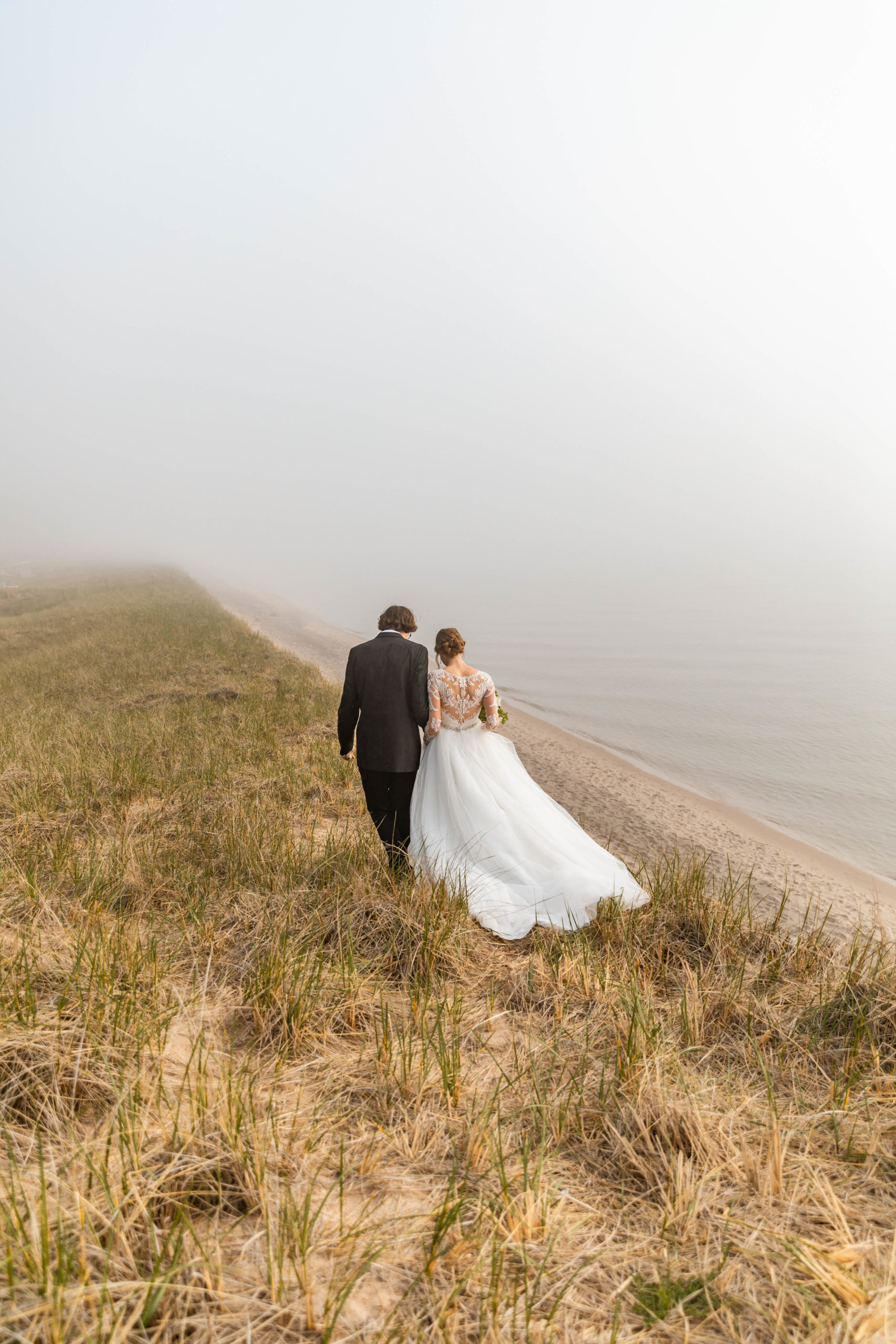 bride and groom walking on sand dunes at the beach in Lake Michigan
