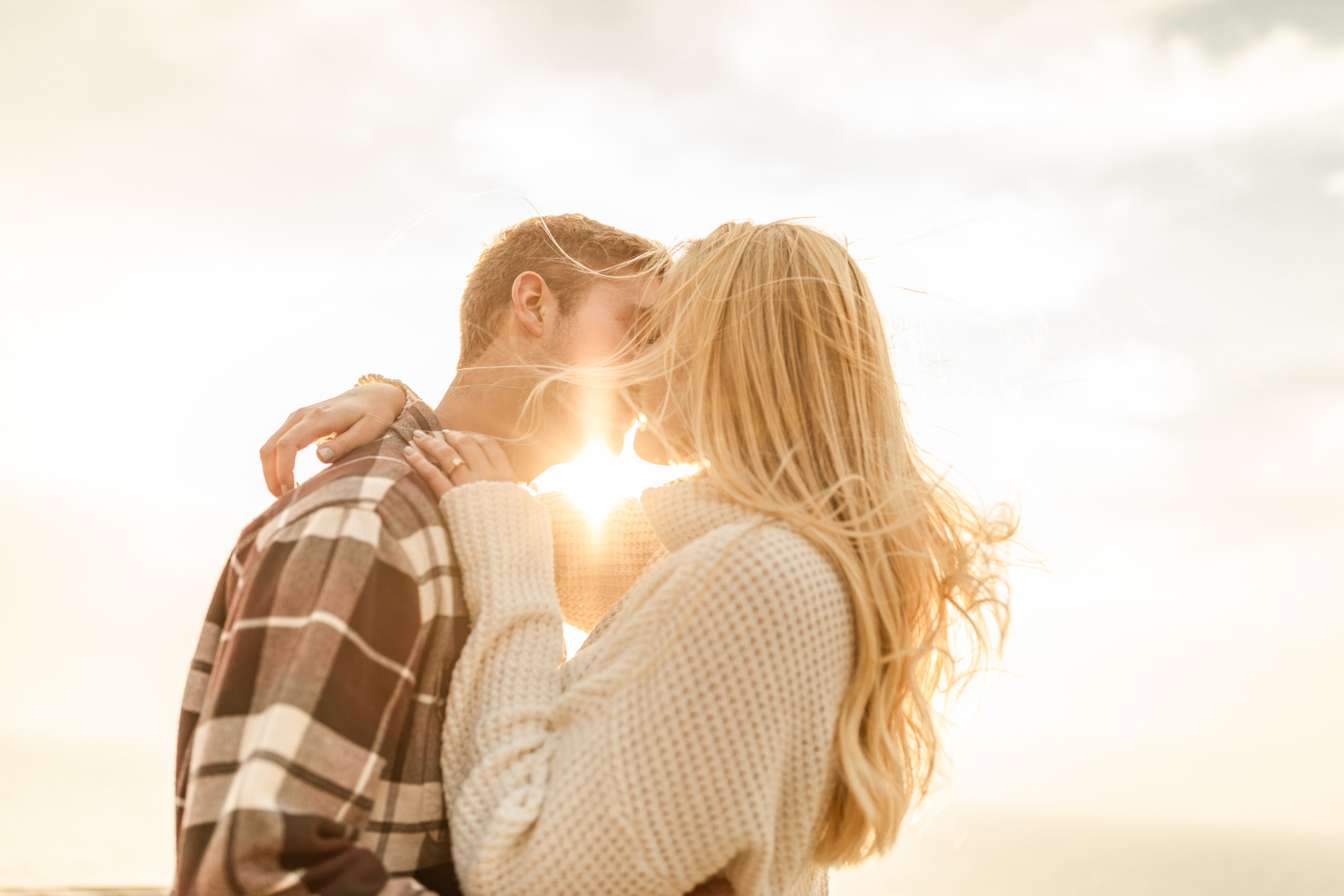 couple kissing on the beach at sunset in engagement photos at Lake Michigan
