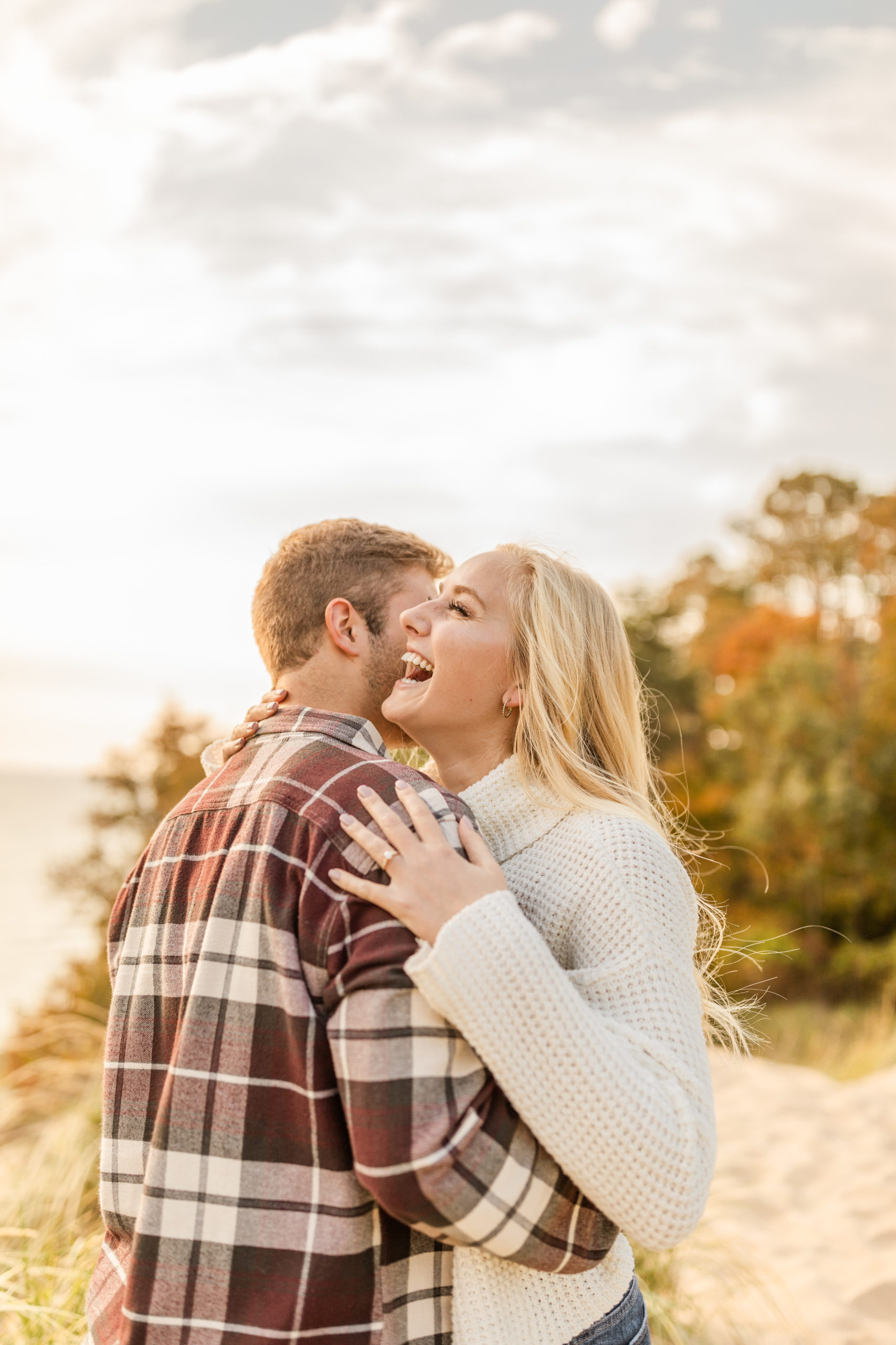 couple hugging and smiling on the beach fall engagement photos