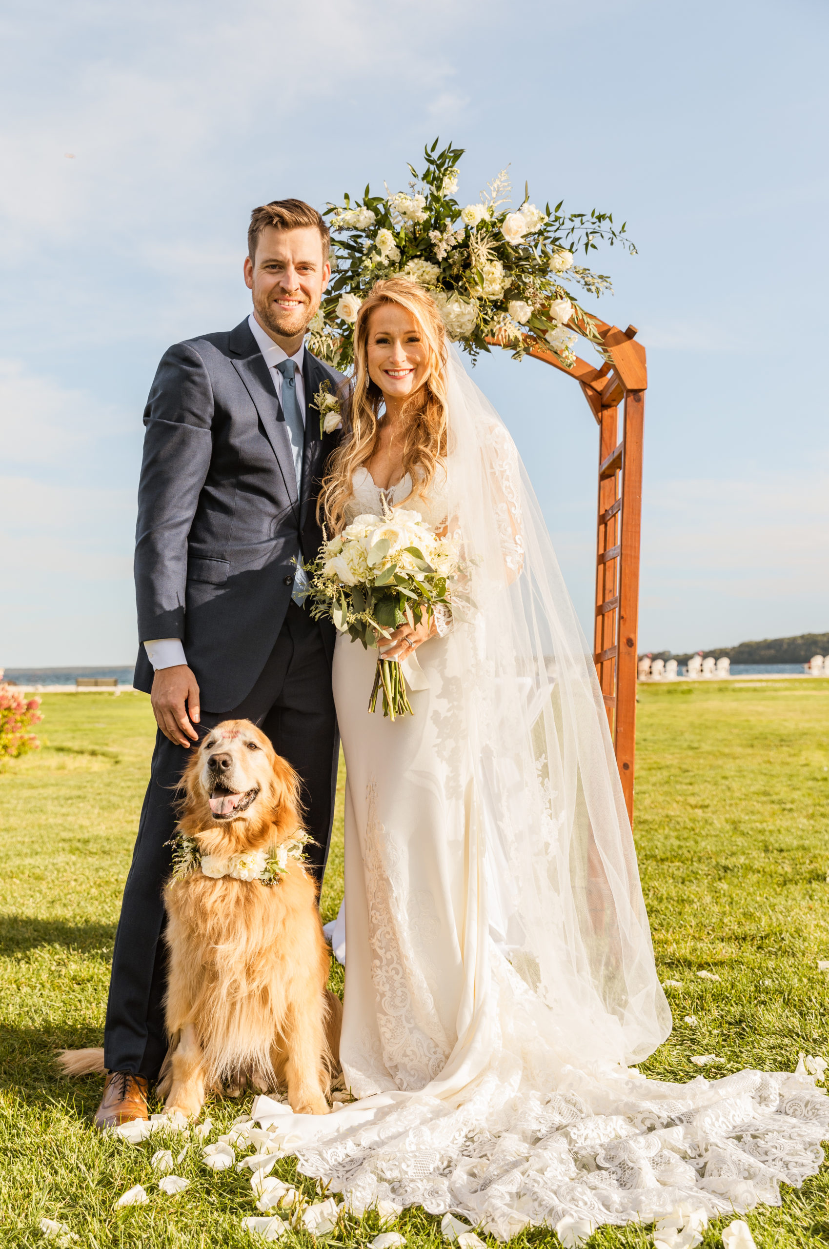 Bride and groom posting with golden retriever on Mackinac Island lawn