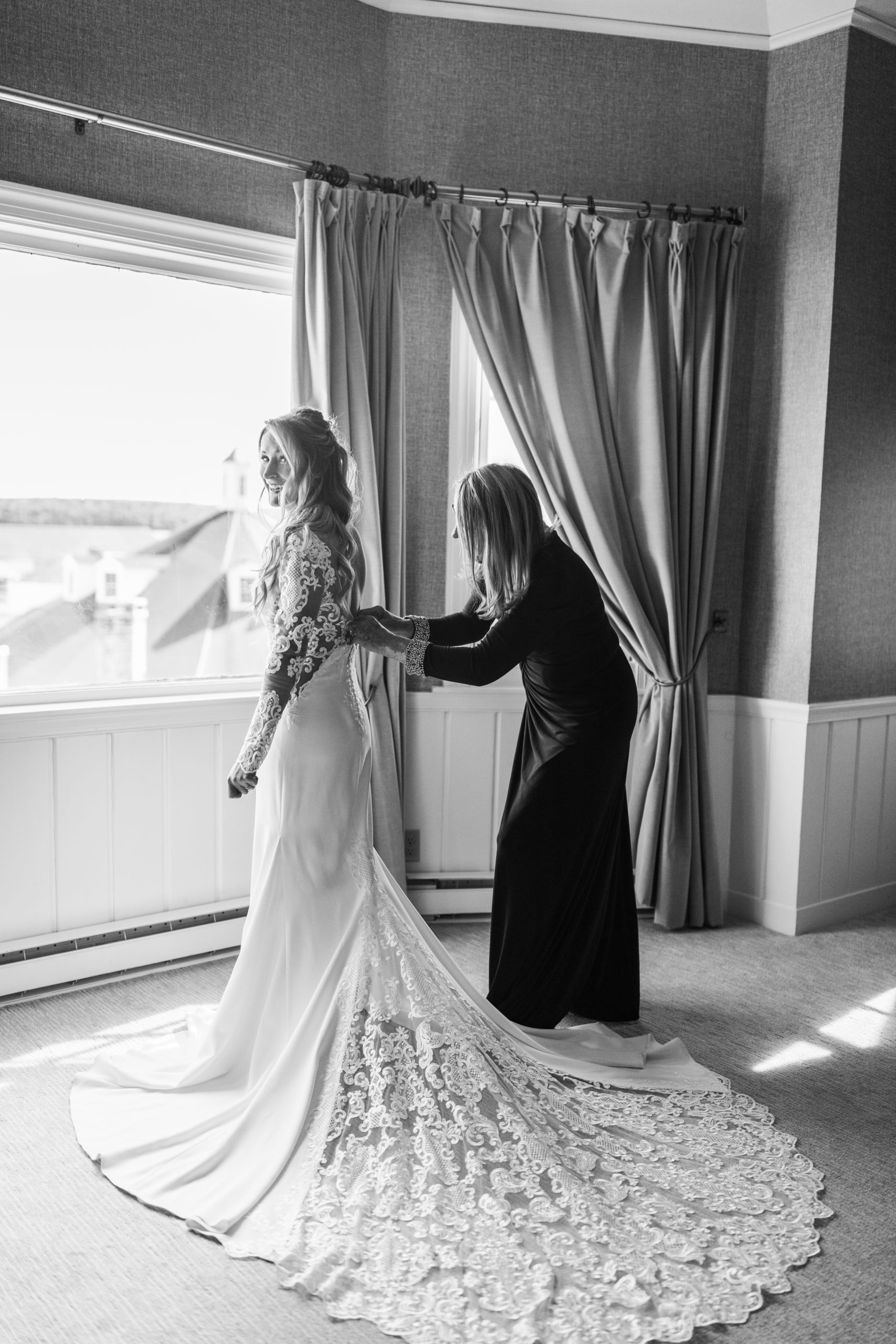 Mother helping daughter put on wedding dress