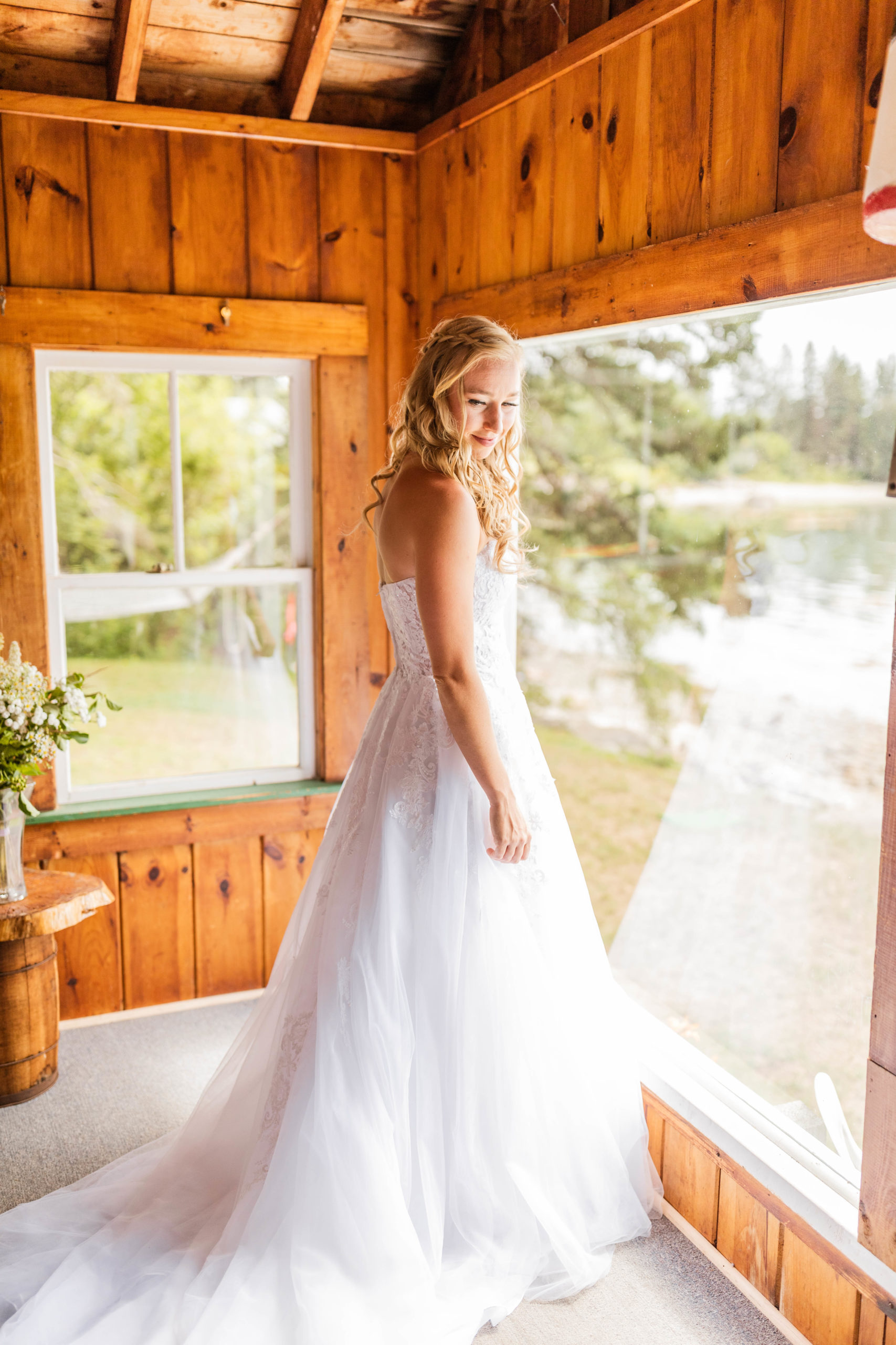 bride in wedding dress standing in front of cabin window