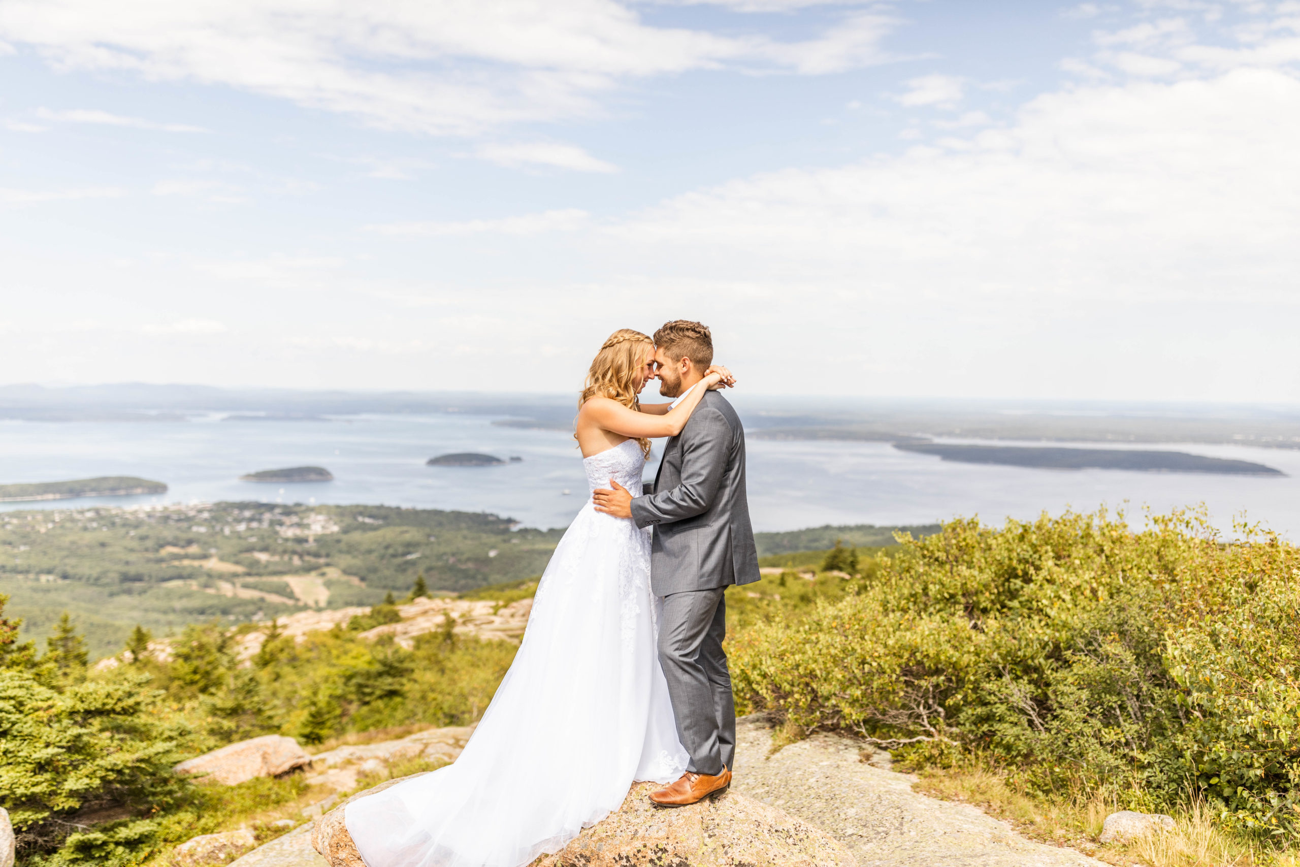 bride and groom standing on rocks overlooking ocean at Acadia National Park elopement