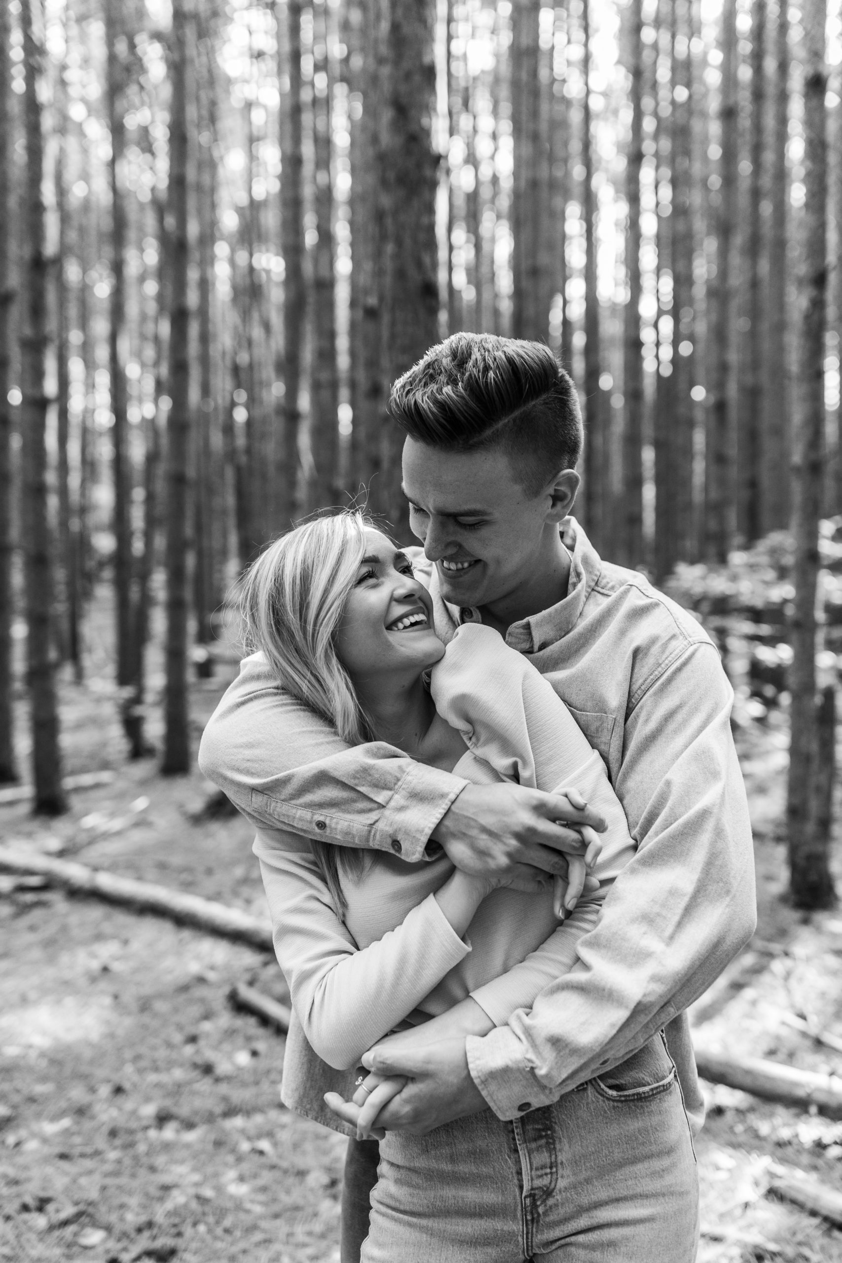 couple hugging in a wooded forest for Michigan engagement photos