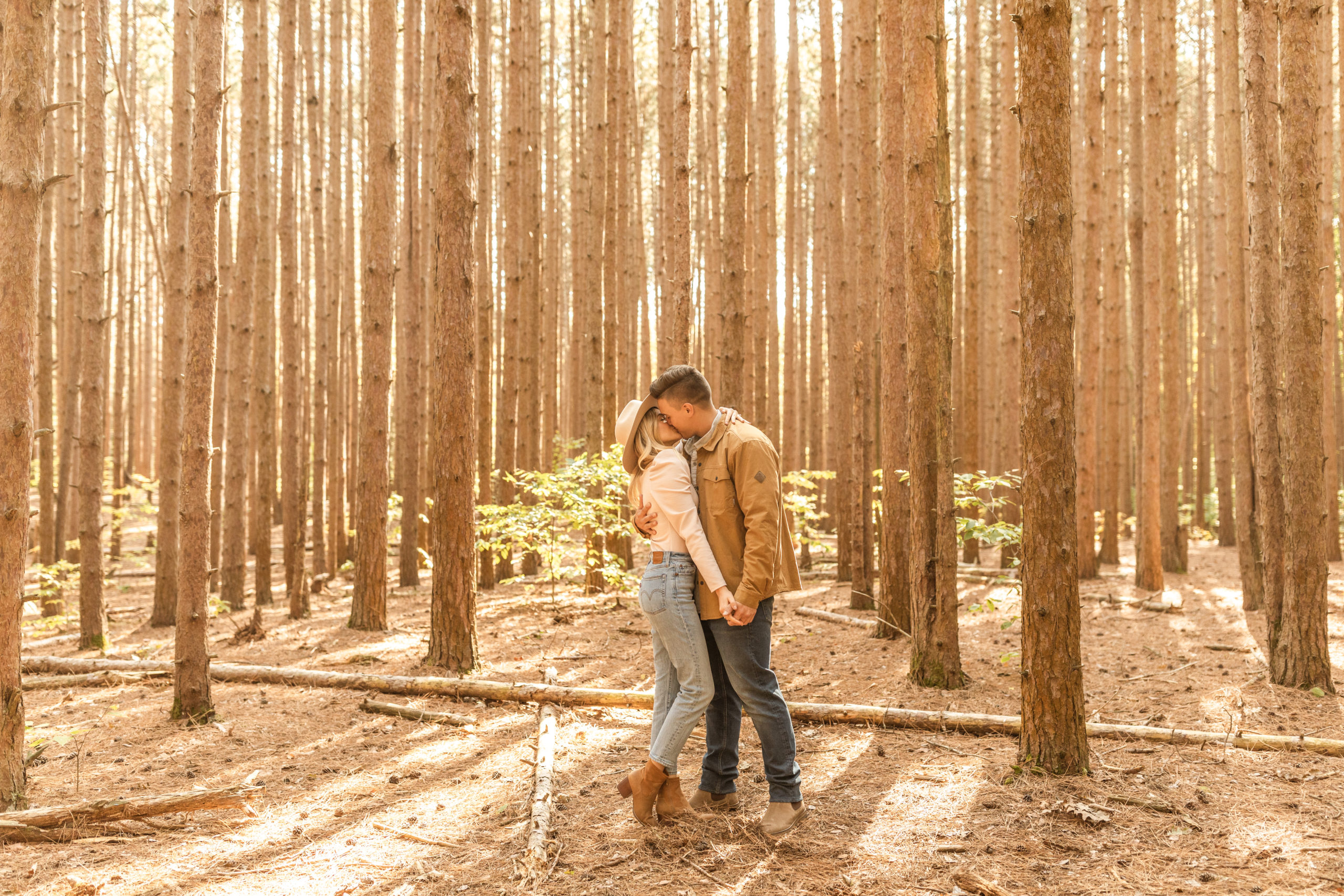 boho couple kissing in wooded forest in Michigan