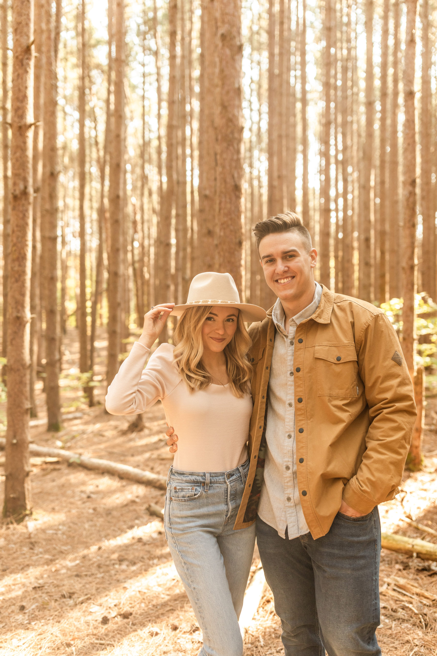 boho couple posing in wooded forest for engagement photos