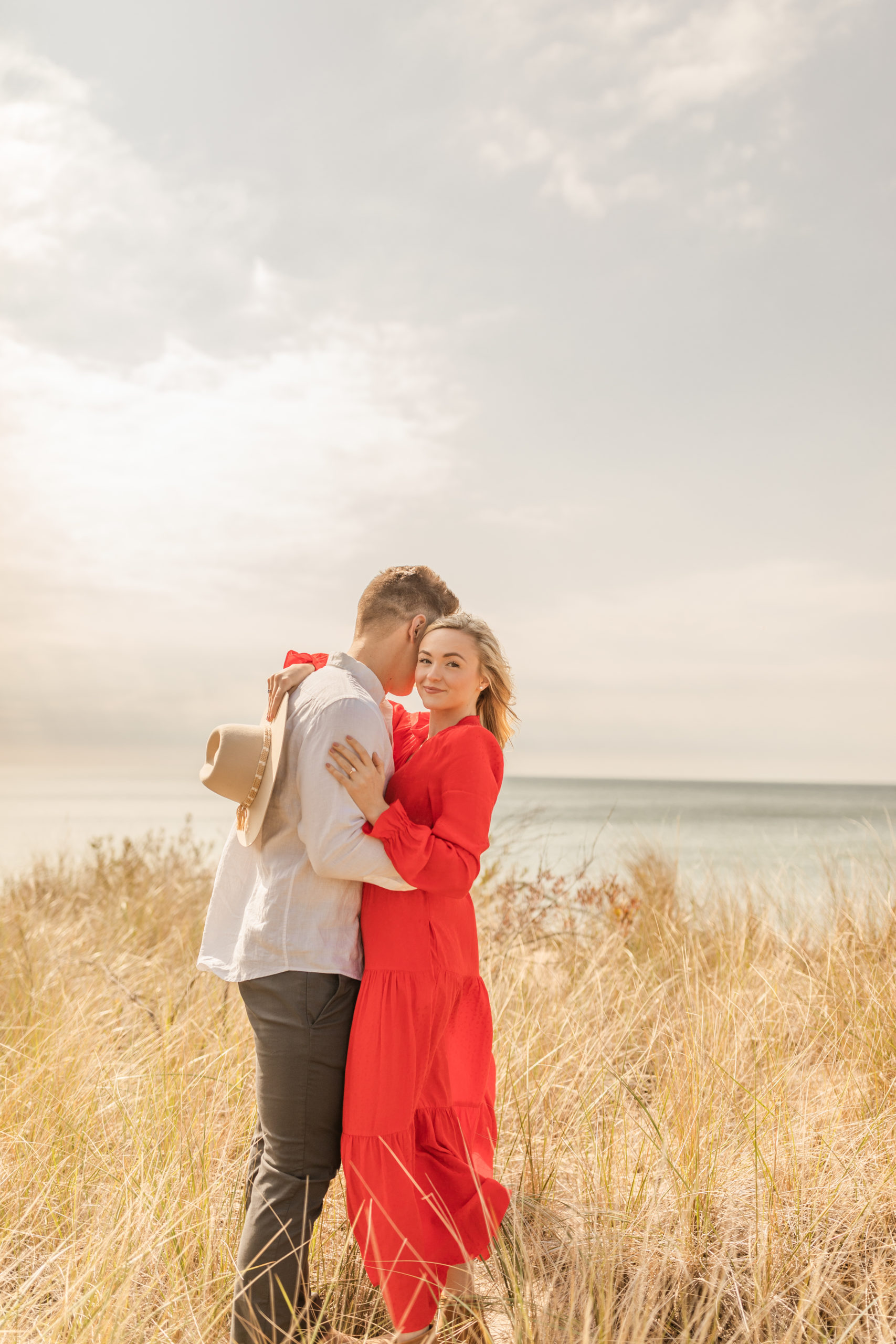 boho couple hugging on the beach for engagement photo session
