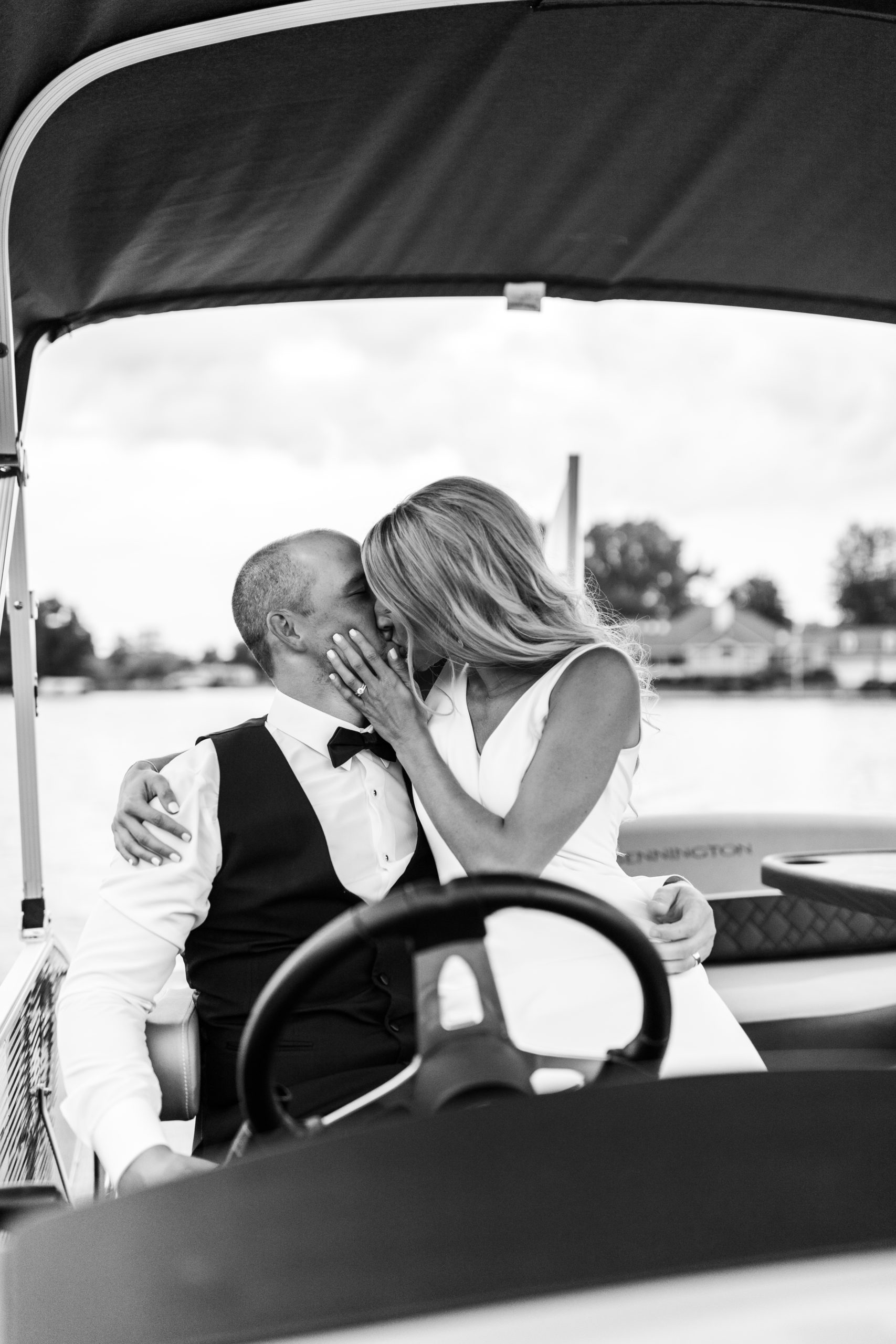 bride and groom kissing on pontoon boat at lakefront wedding