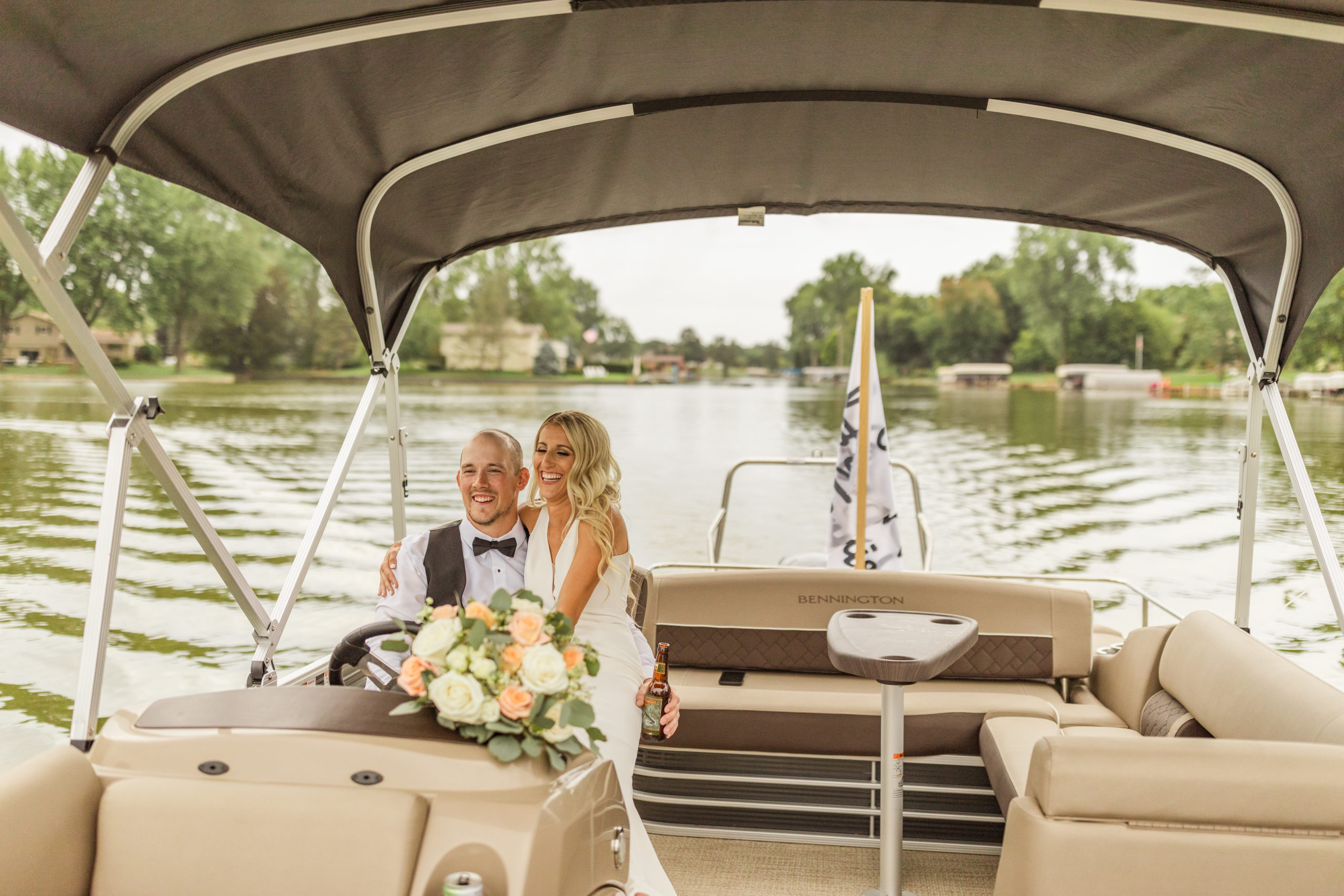 bride and groom driving pontoon on lake in Michigan wedding