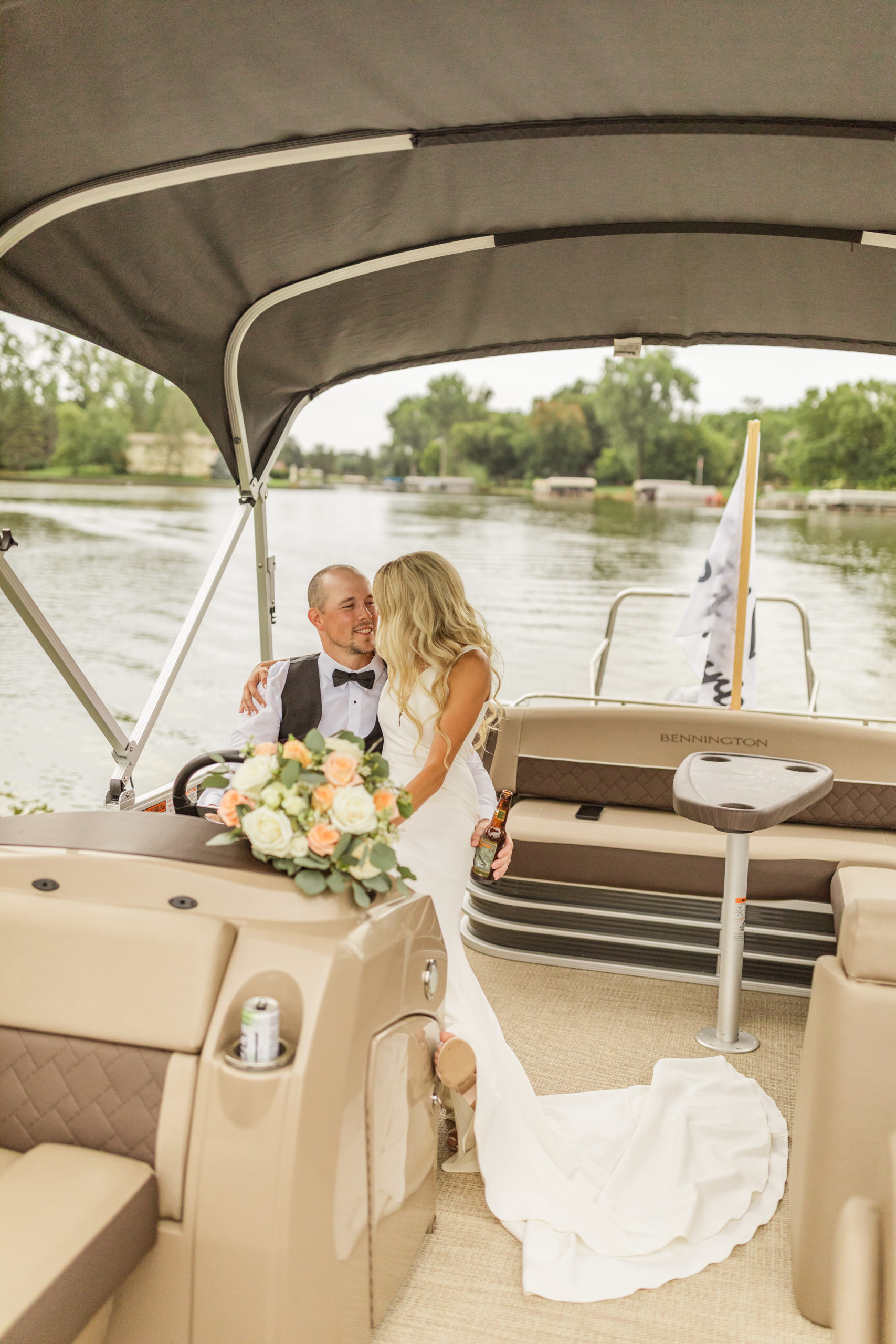 bride and groom driving pontoon on lake in Michigan
