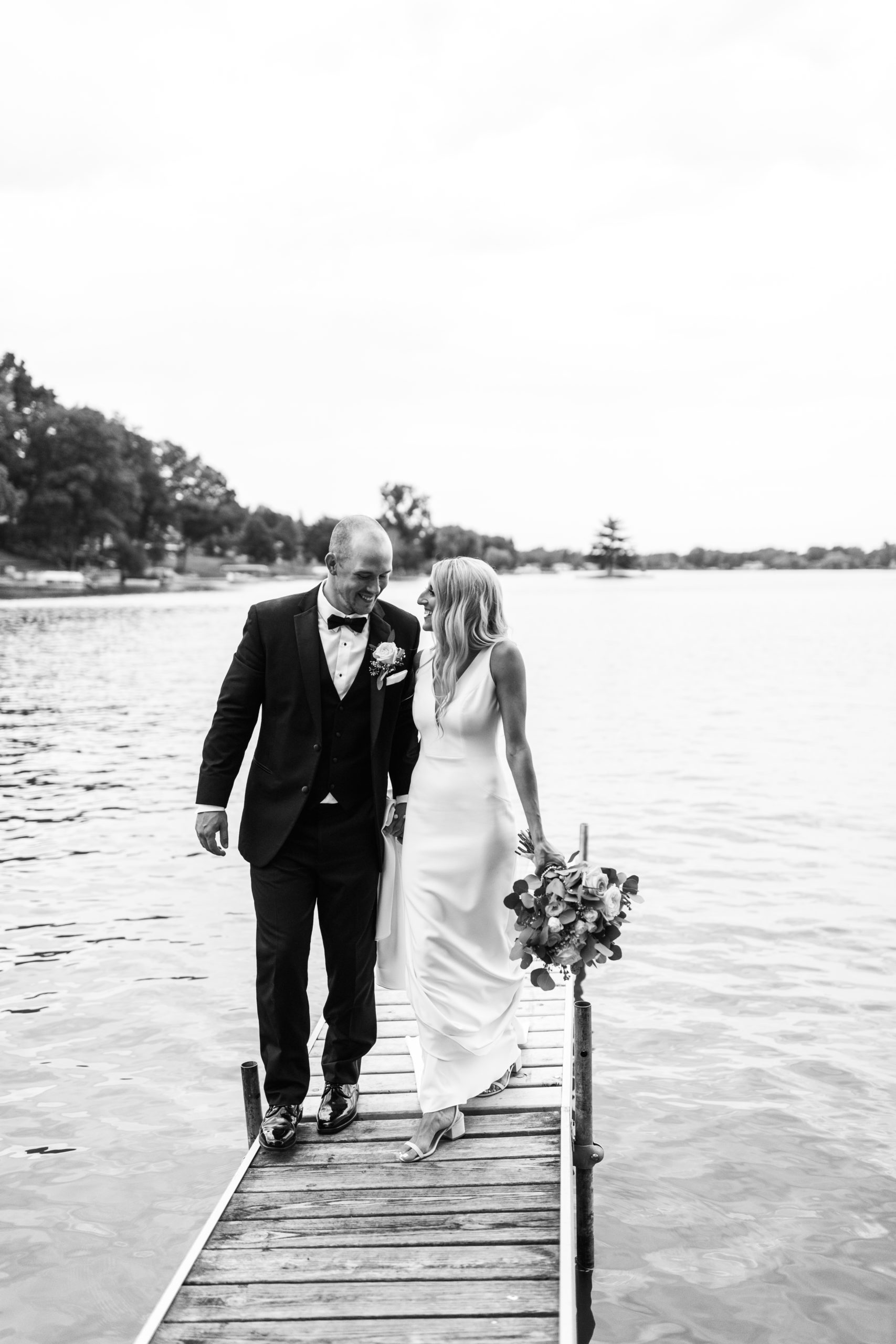 bride and groom holding hands on dock on Michigan lake wedding