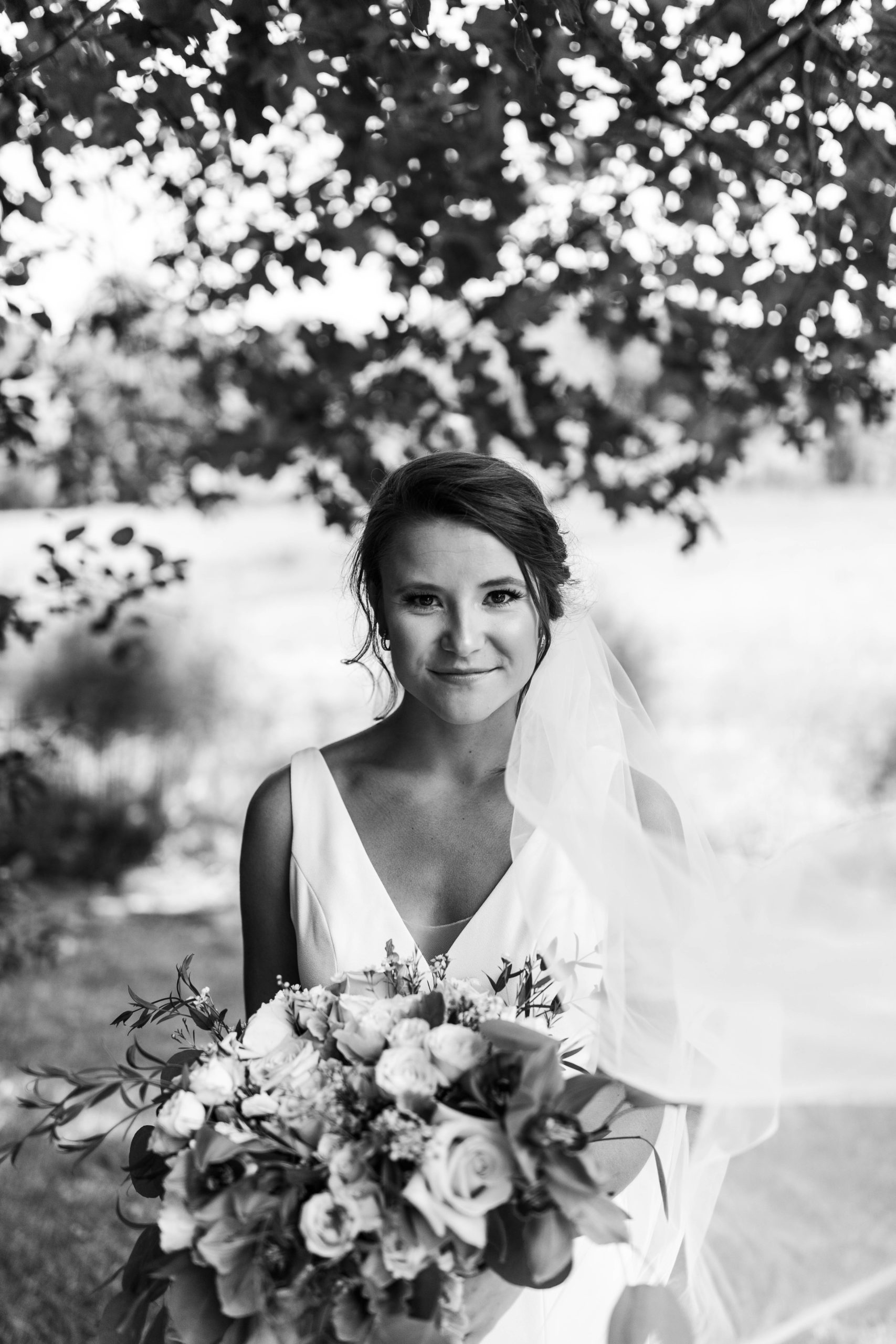 bride smiling holding bouquet with veil
