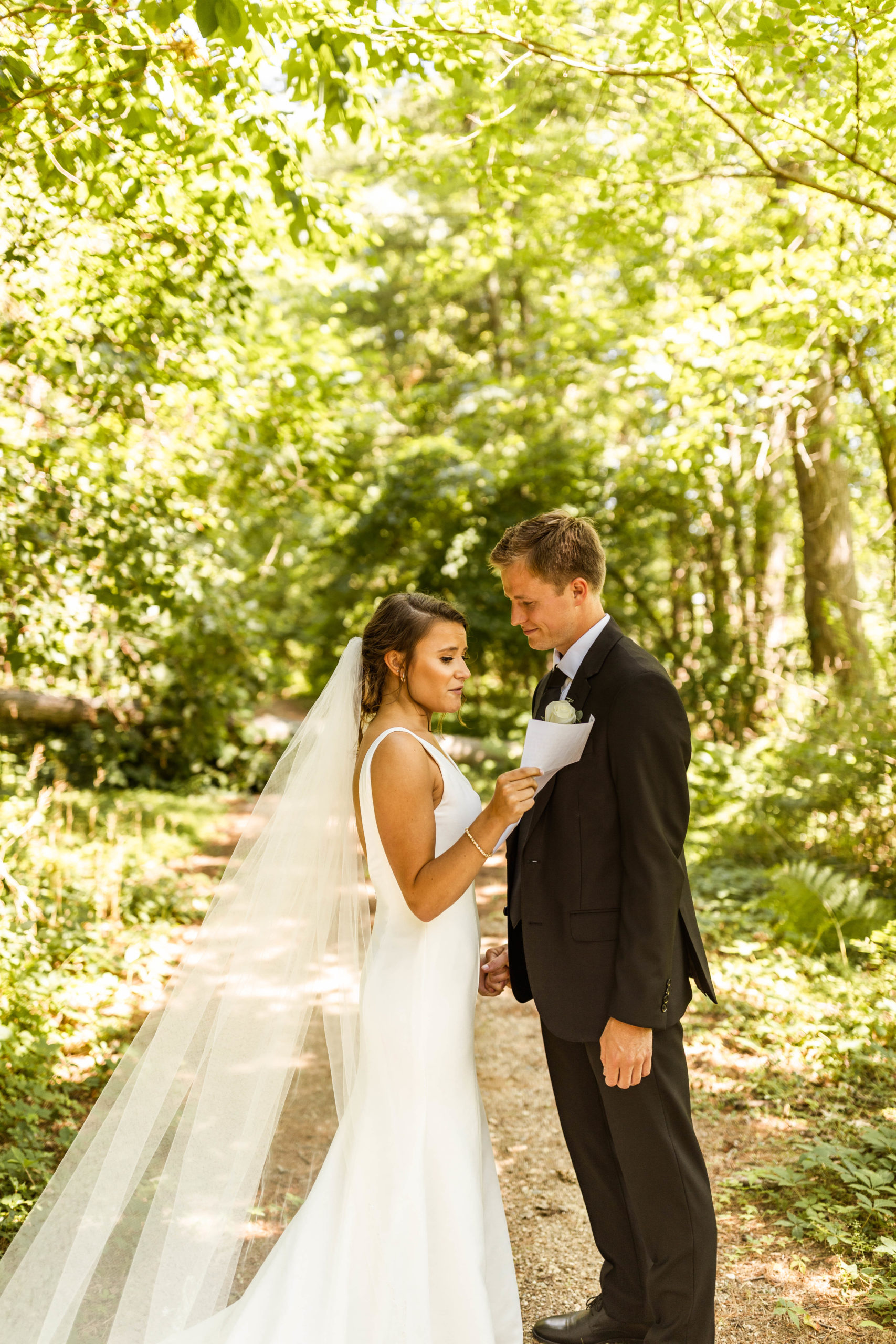 bride reading emotional letter to groom in the woods
