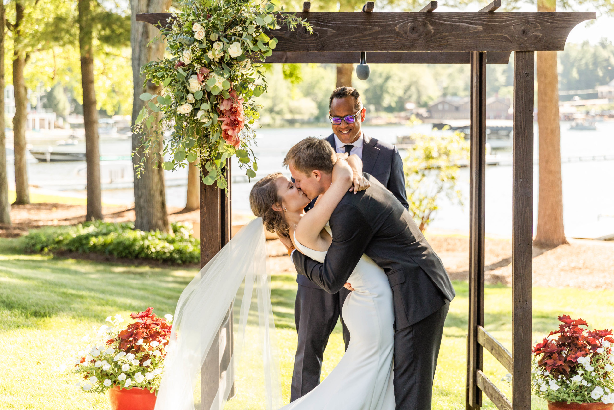 bride and groom kissing under pergola at Lakefront Wedding ceremony in Michigan