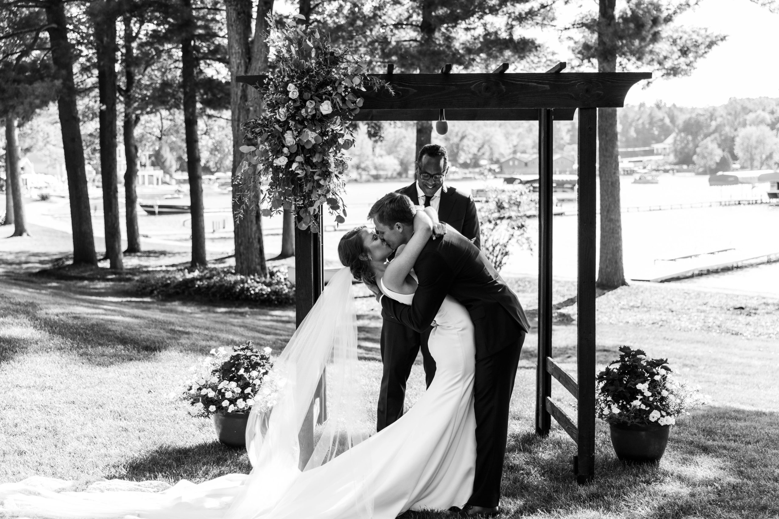 bride and groom kissing under pergola at Lakefront Wedding ceremony