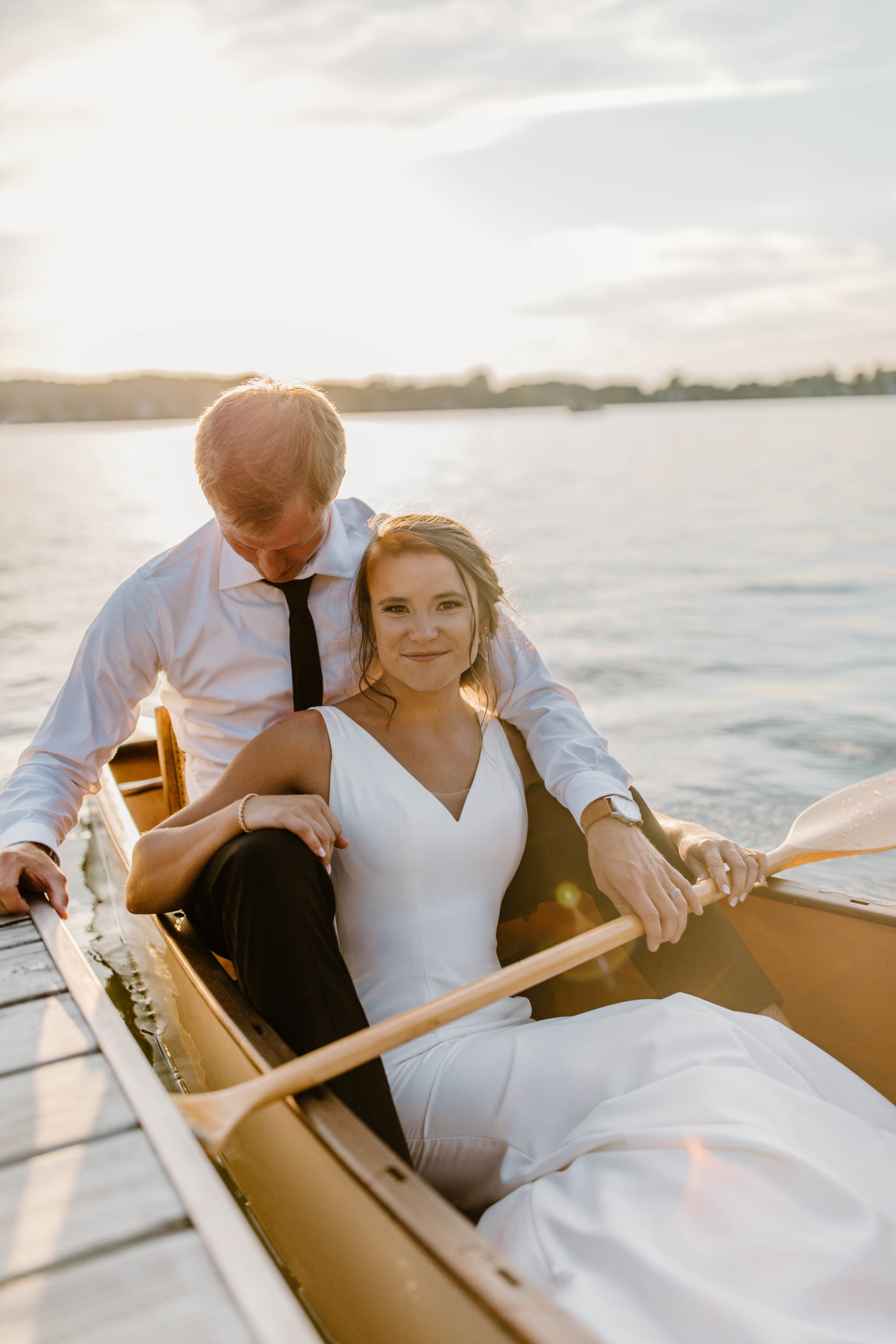 bride and groom in canoe on a lake at sunset
