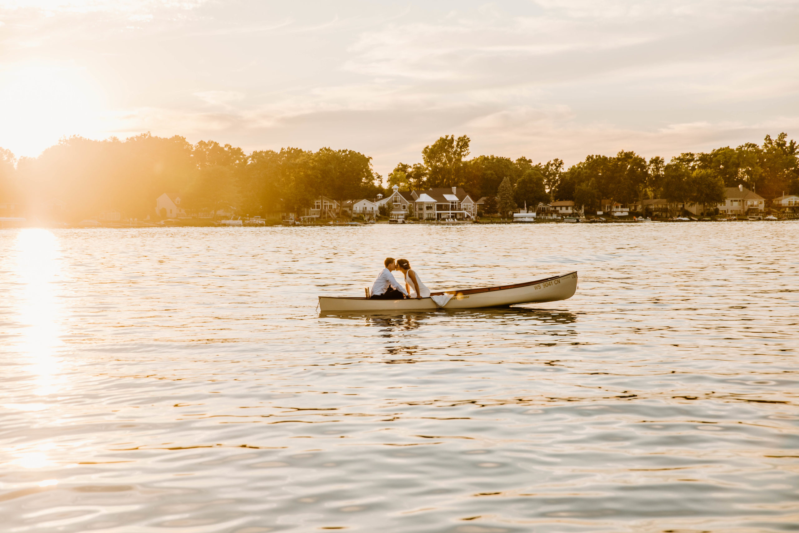 bride and groom in canoe on a lake at sunset