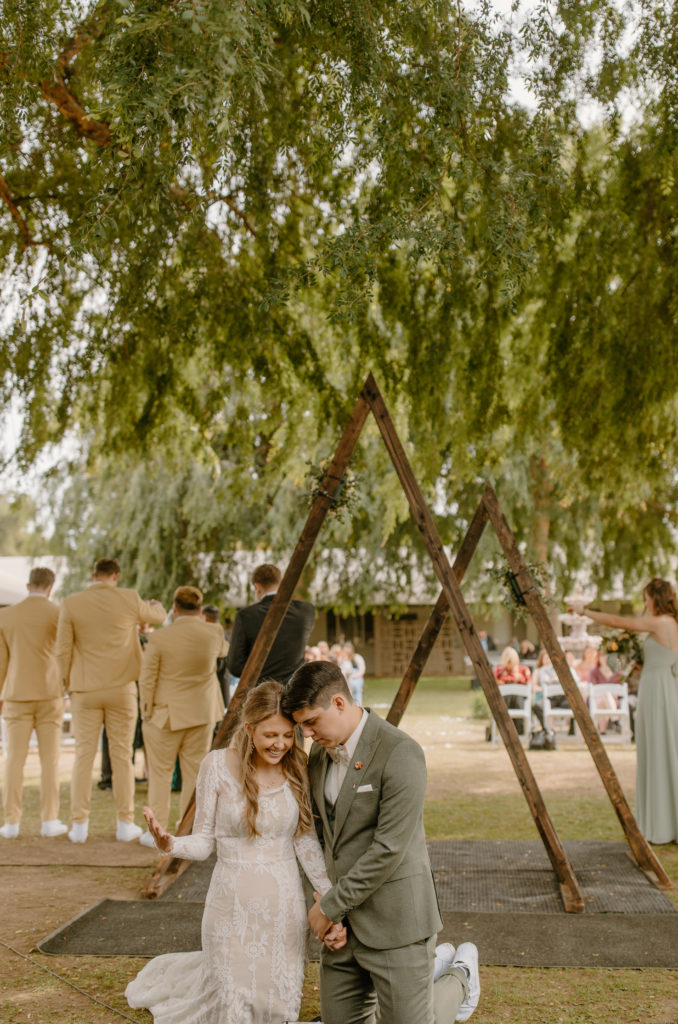 Bride and Groom Candid Ceremony Wedding Photos prayer on knees under willow trees