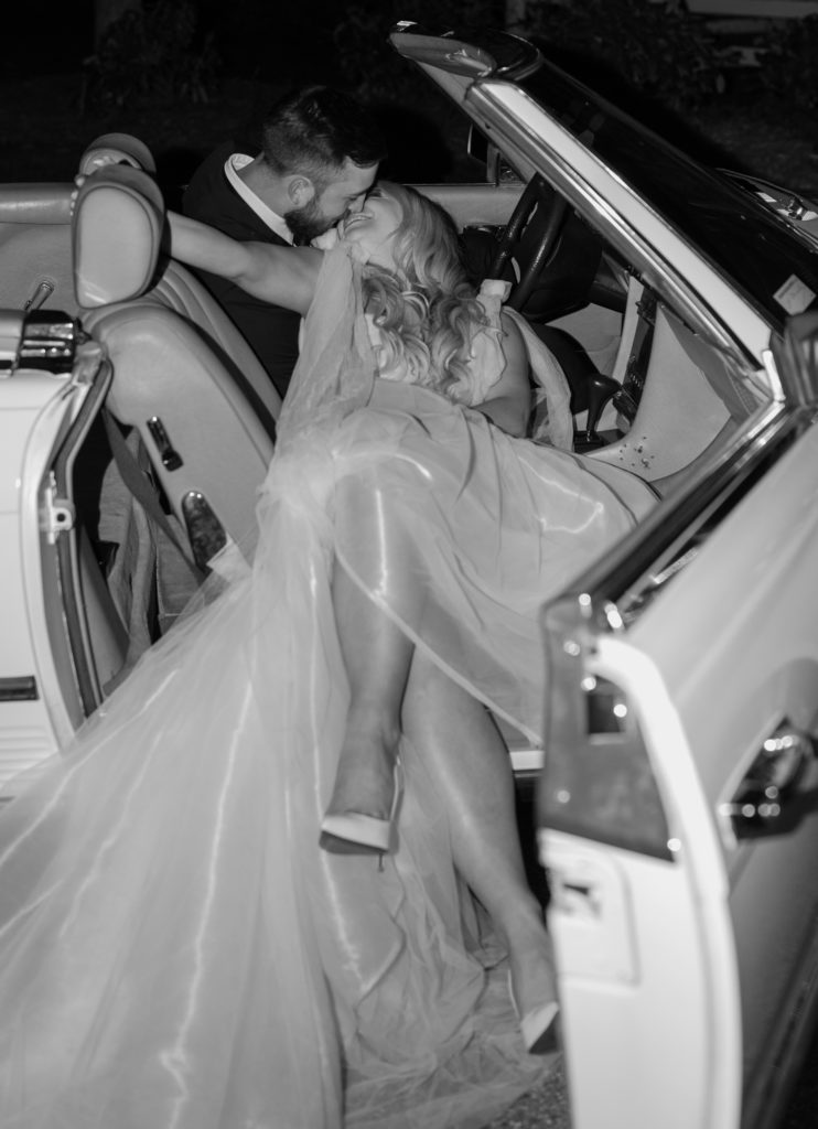 Vintage car at wedding reception getaway car bride and groom kissing in vintage car